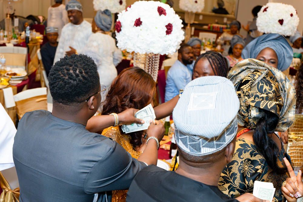 Attendees gather at an elegant celebration with white and red floral decorations.