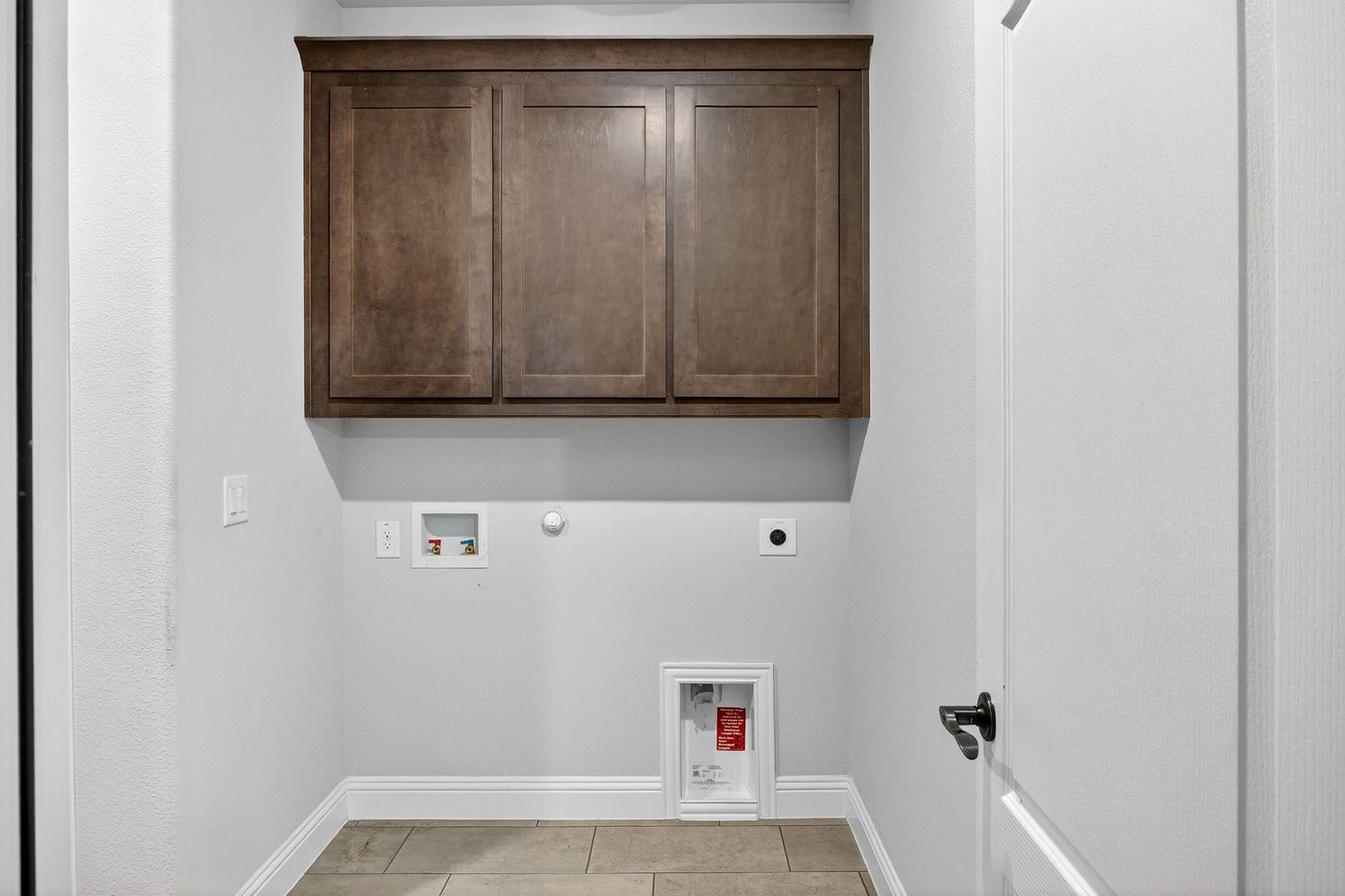 Kitchen view showing dark wood cabinets and white walls with doorway entrance.