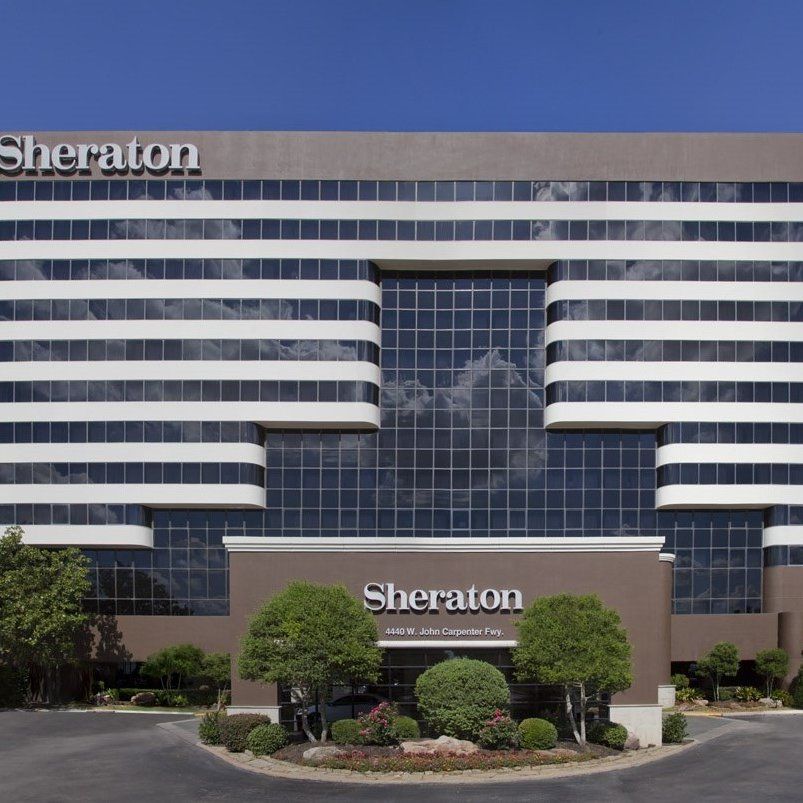 Exterior view of Sheraton hotel building with glass windows and landscaped entrance.