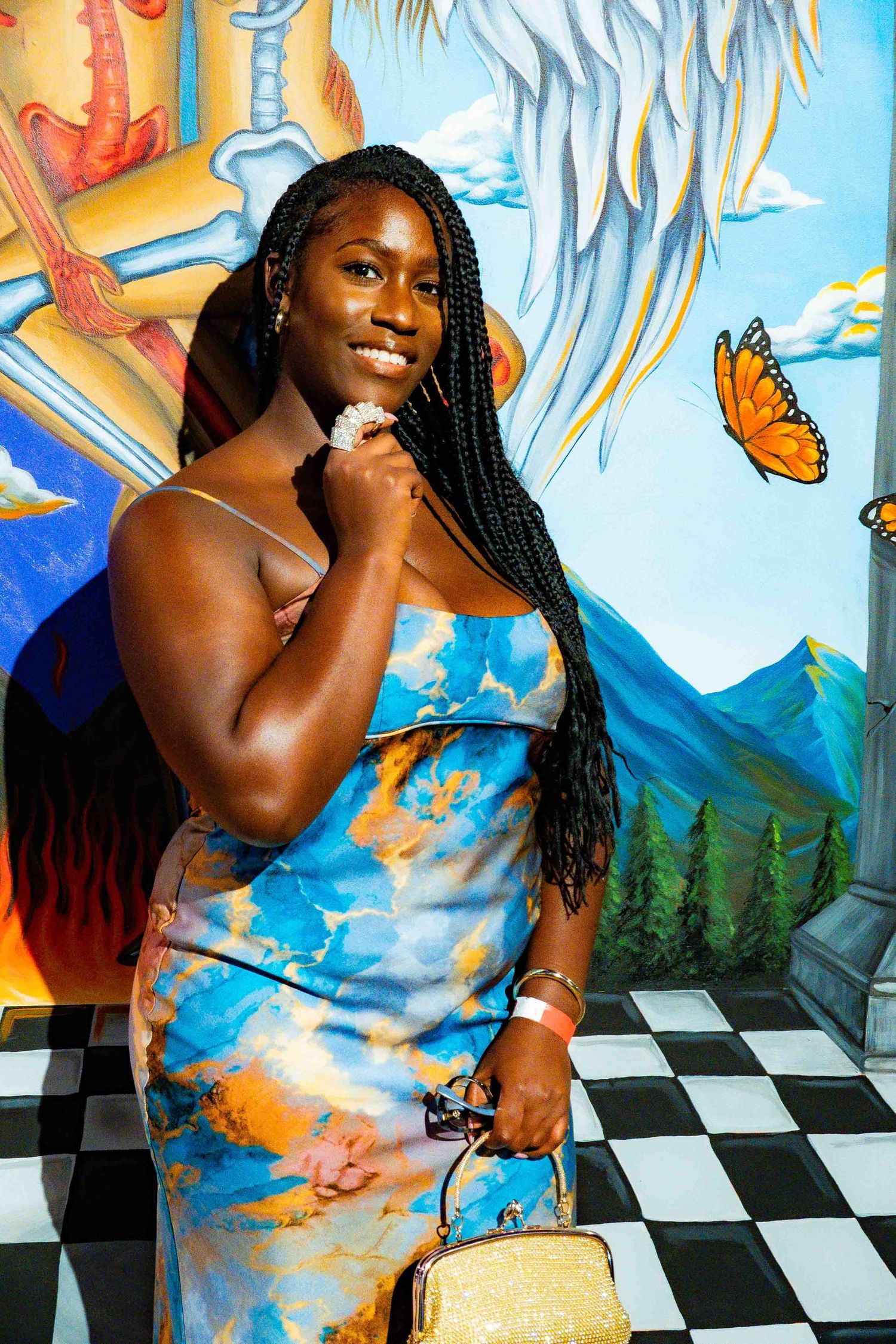 Colorful photoshoot with a checkered floor and painted butterfly mural backdrop.