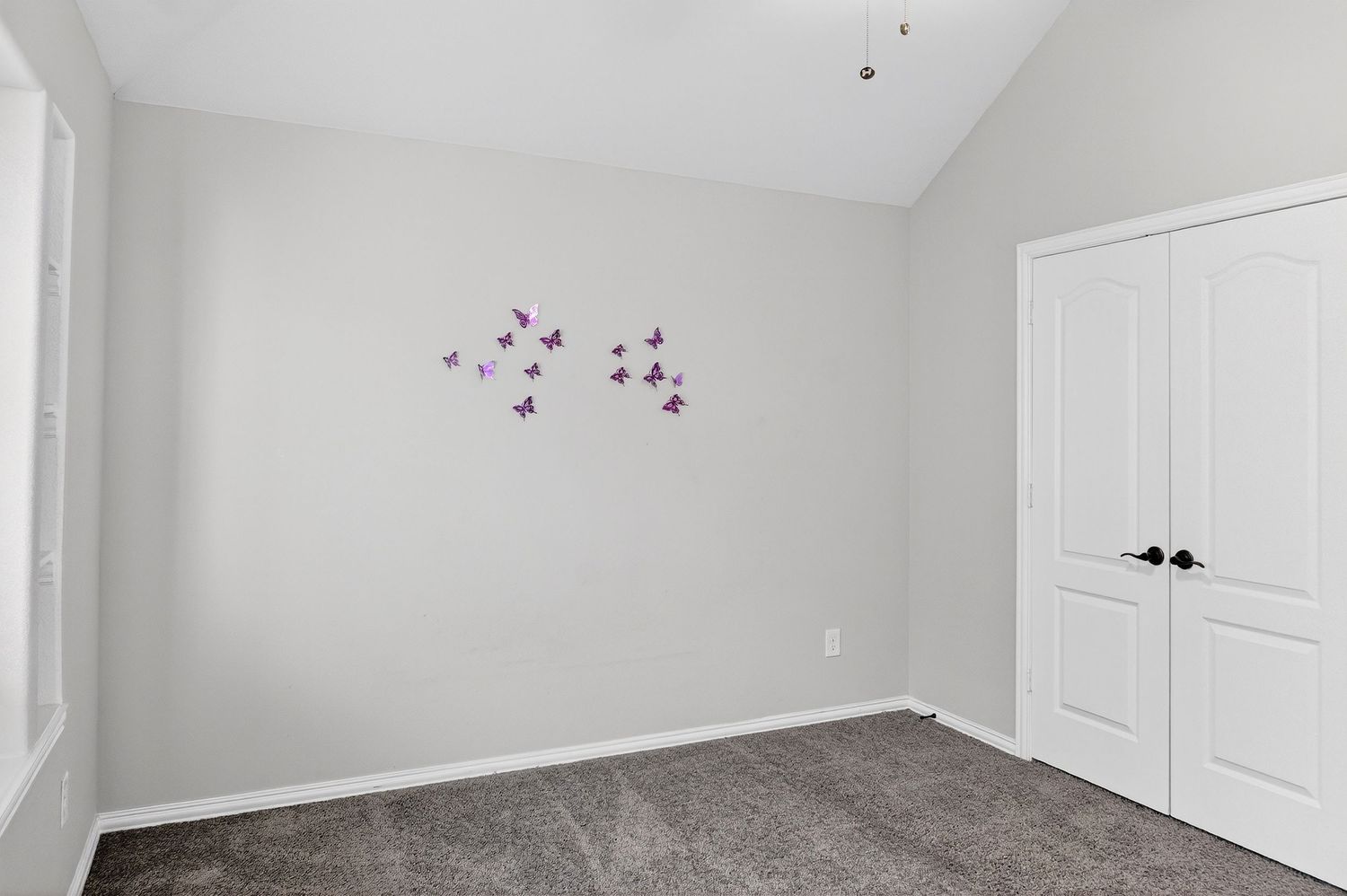 Bright room with high ceilings, white doors, and gray carpeting throughout.