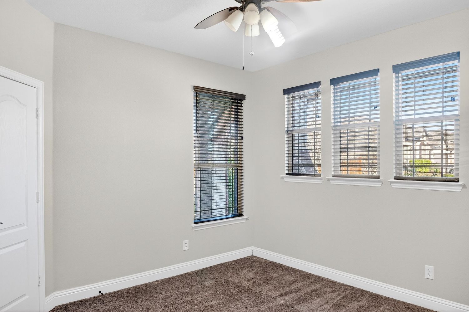 Spacious bedroom with vaulted ceiling, ceiling fan, and neutral gray walls features plush carpeting.