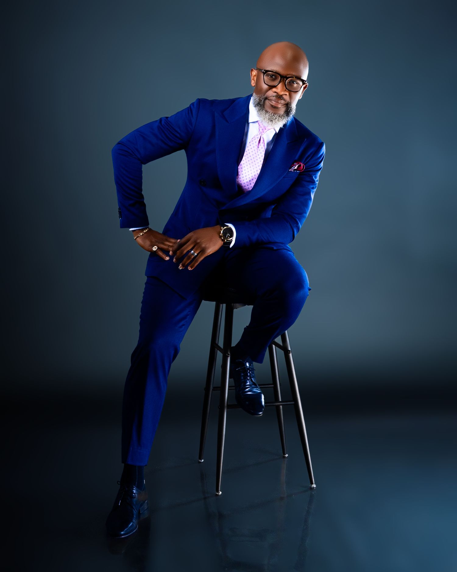 Elegant studio photoshoot featuring a royal blue suit and relaxed seated poses.