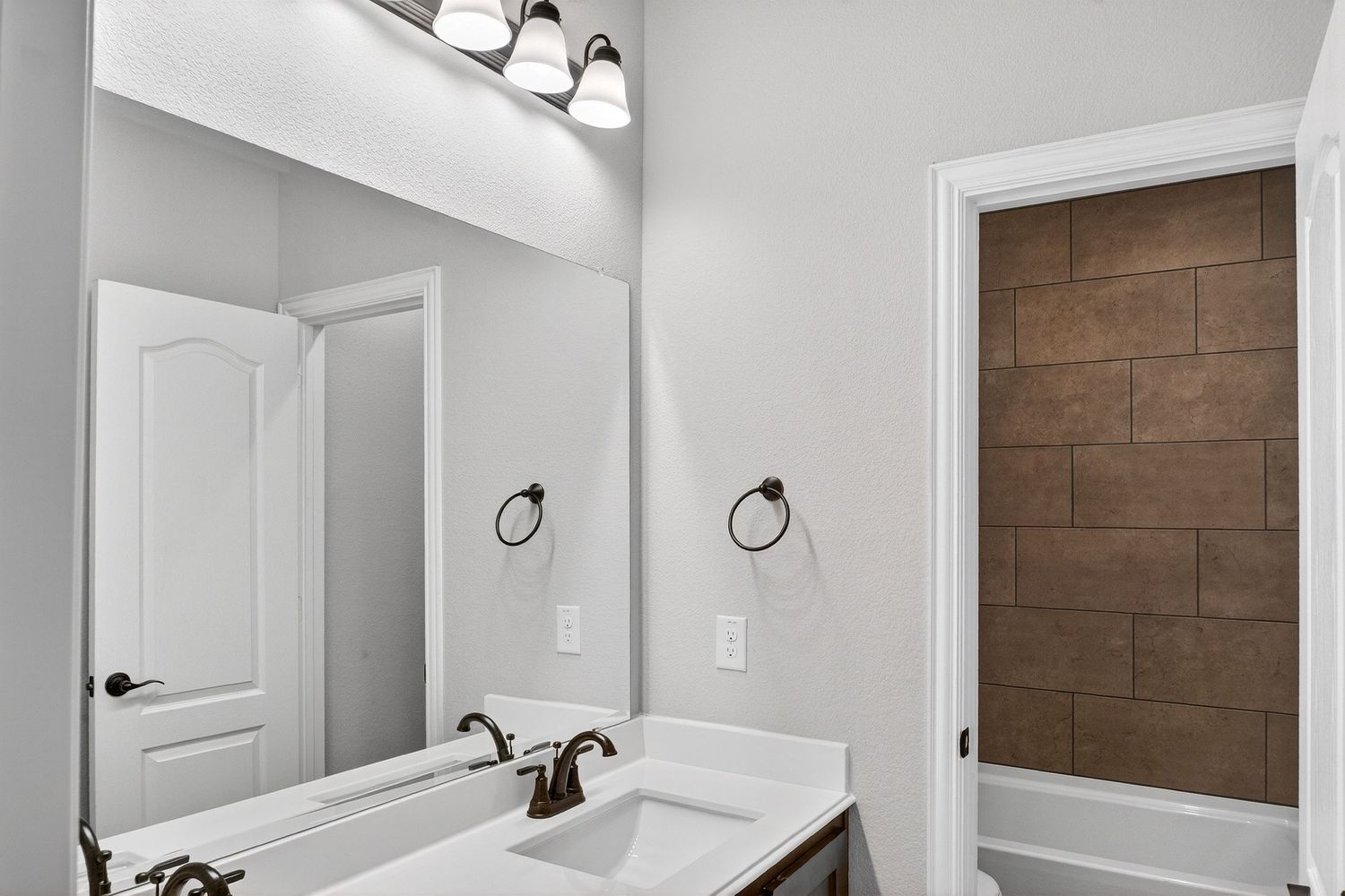 Modern bathroom featuring white vanity, framed mirror, and decorative wood accent wall.