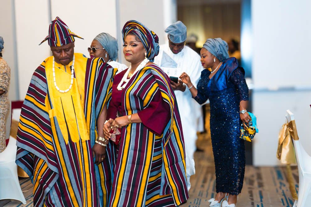 Group wearing traditional African attire with colorful striped patterns at formal event.