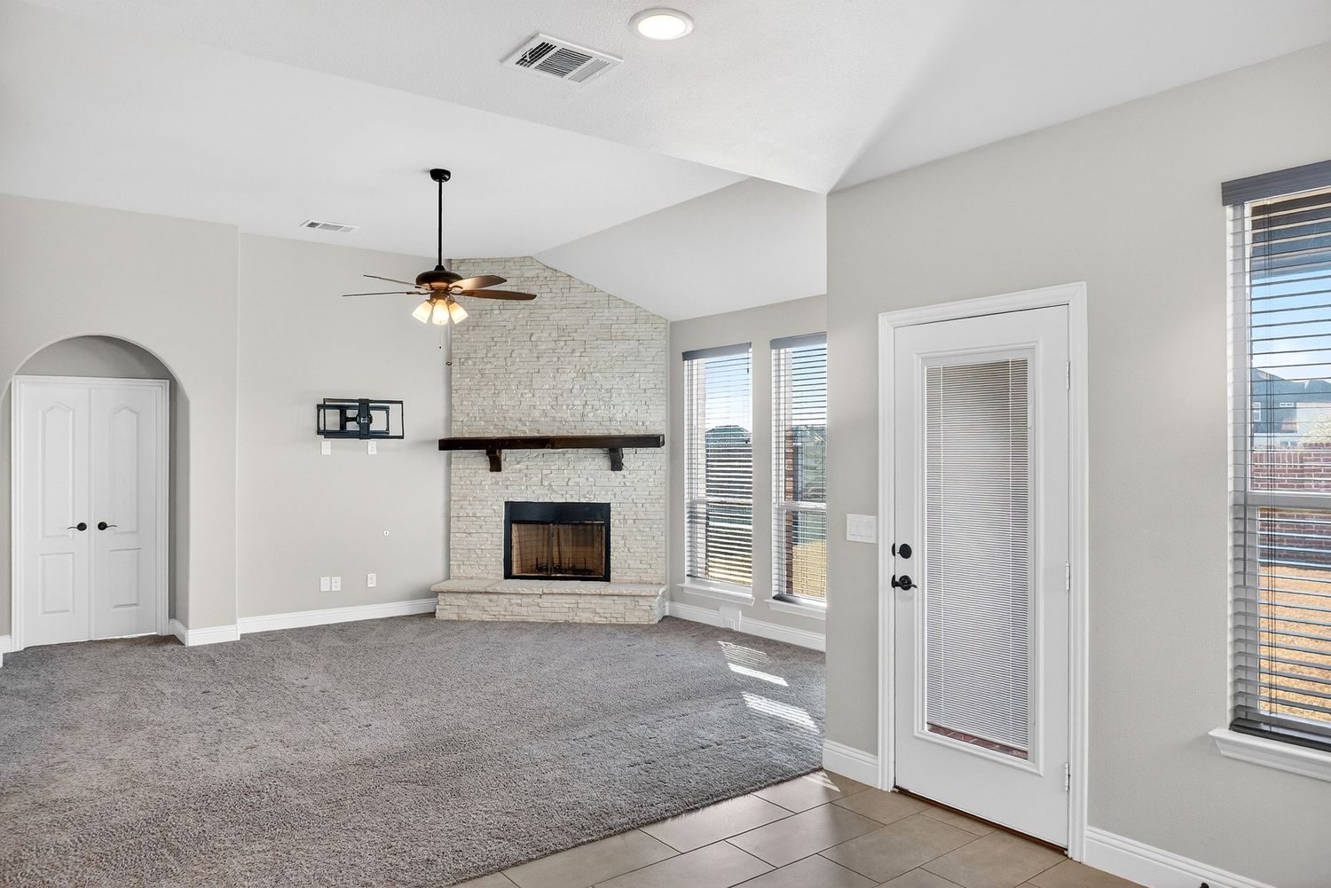Living room with fireplace, carpeted area, and large windows leading to outdoor patio space.