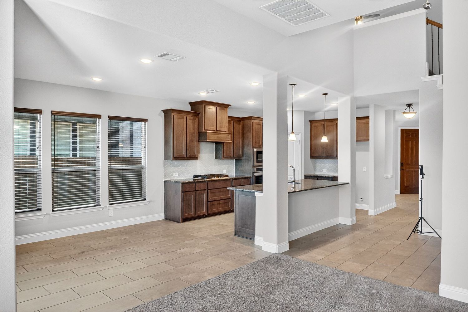 Open concept living space with modern kitchen featuring wood cabinets and large windows.