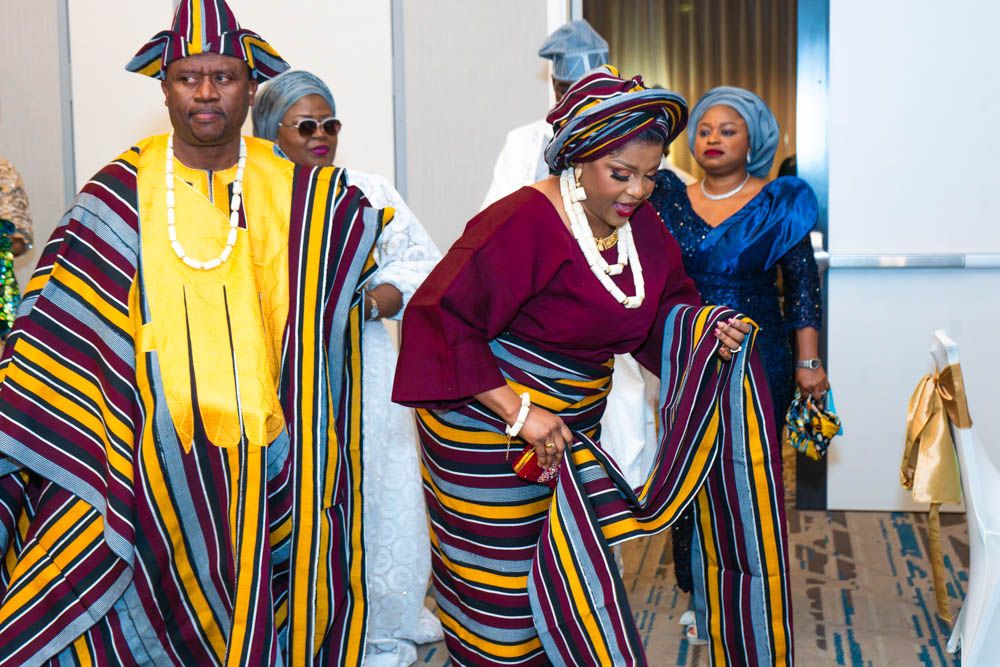 Guests in colorful traditional African clothing socializing at formal event.