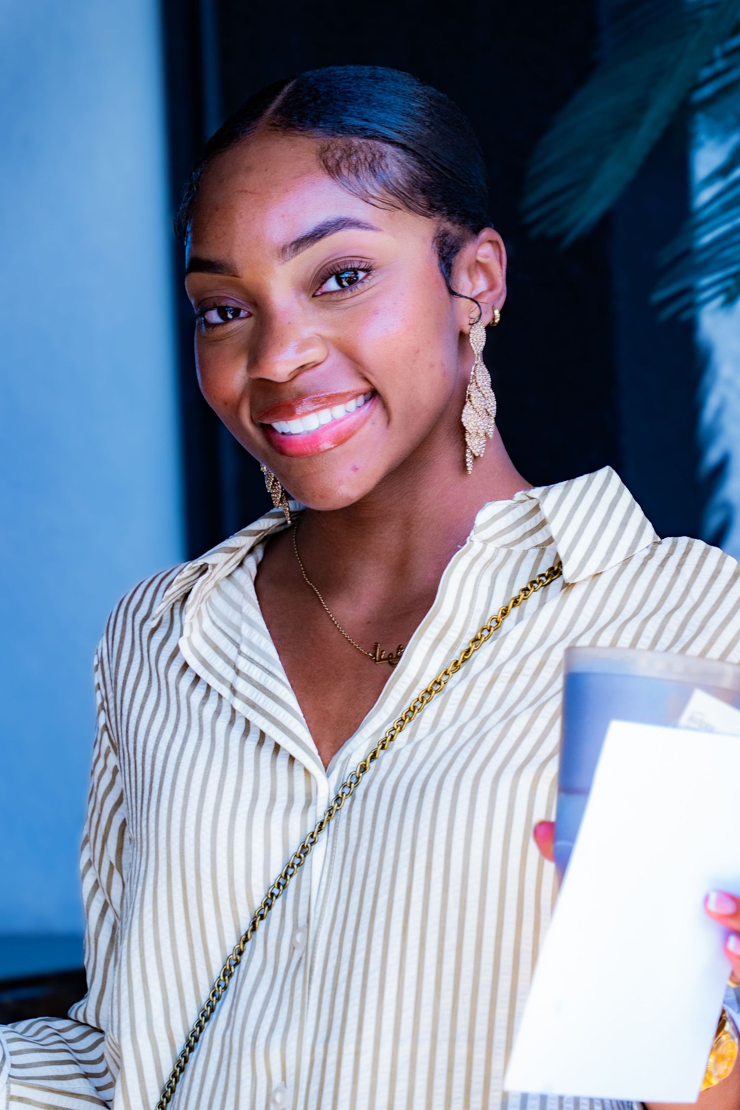 Person in striped white top with jewelry smiling warmly at camera.