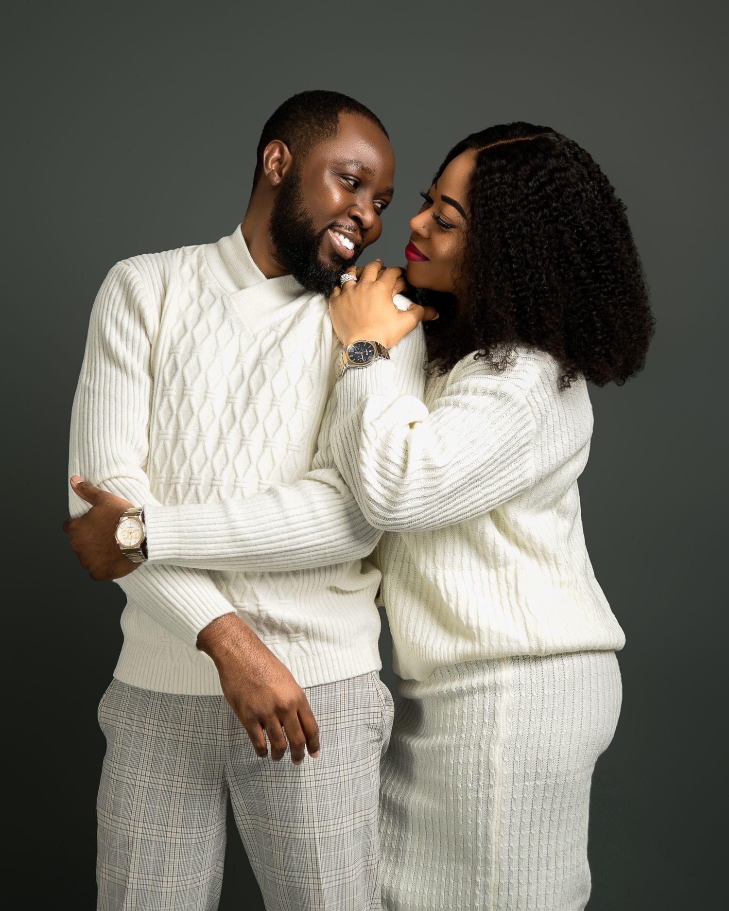 Couple in matching white sweaters share intimate moment during photo session.