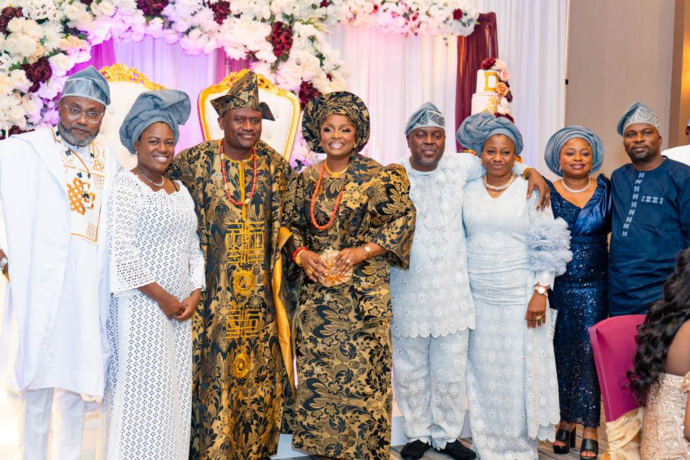 Group photo of celebration attendees wearing traditional African attire and formal wear.