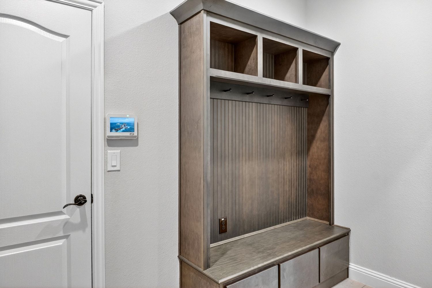 Modern mudroom with built-in wooden storage bench and hooks mounted on paneled wall.
