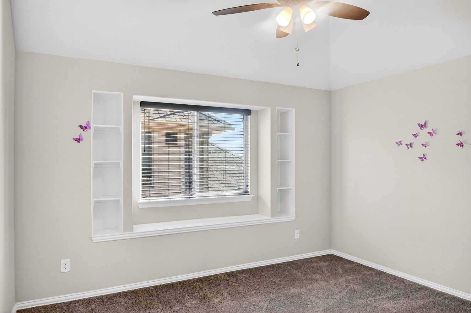 Bedroom with ceiling fan, grey carpet, and windows letting in natural light.