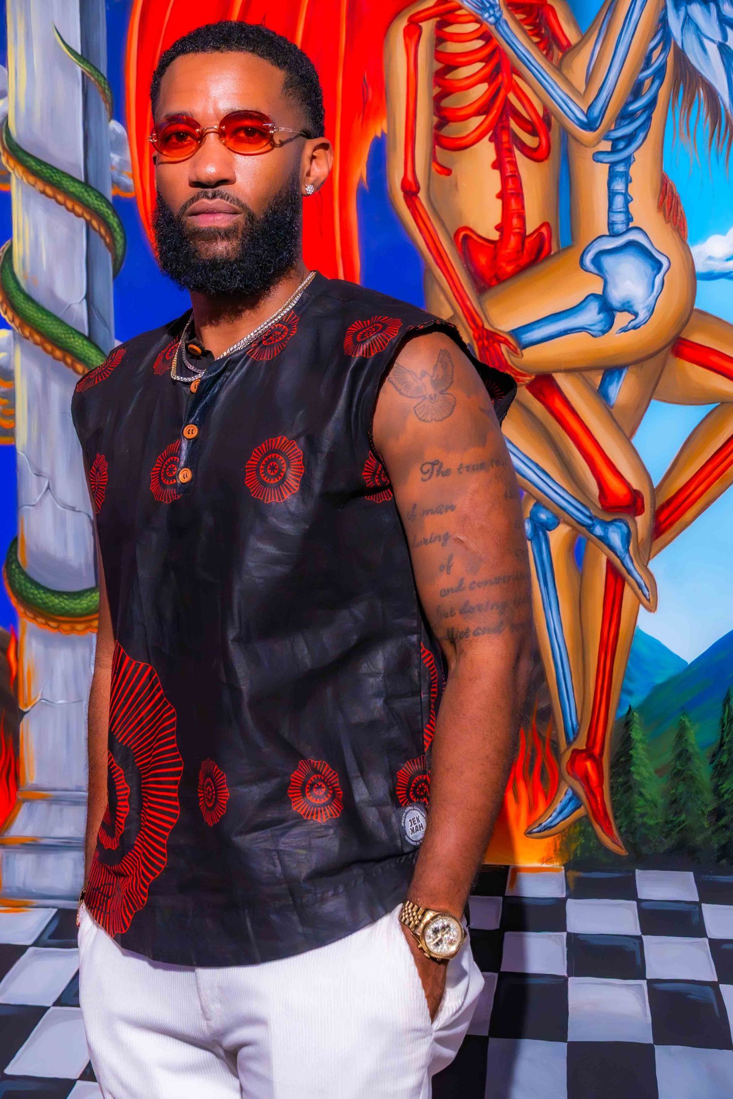 Fashion shoot with black vest against vibrant mural featuring checkered floor pattern.