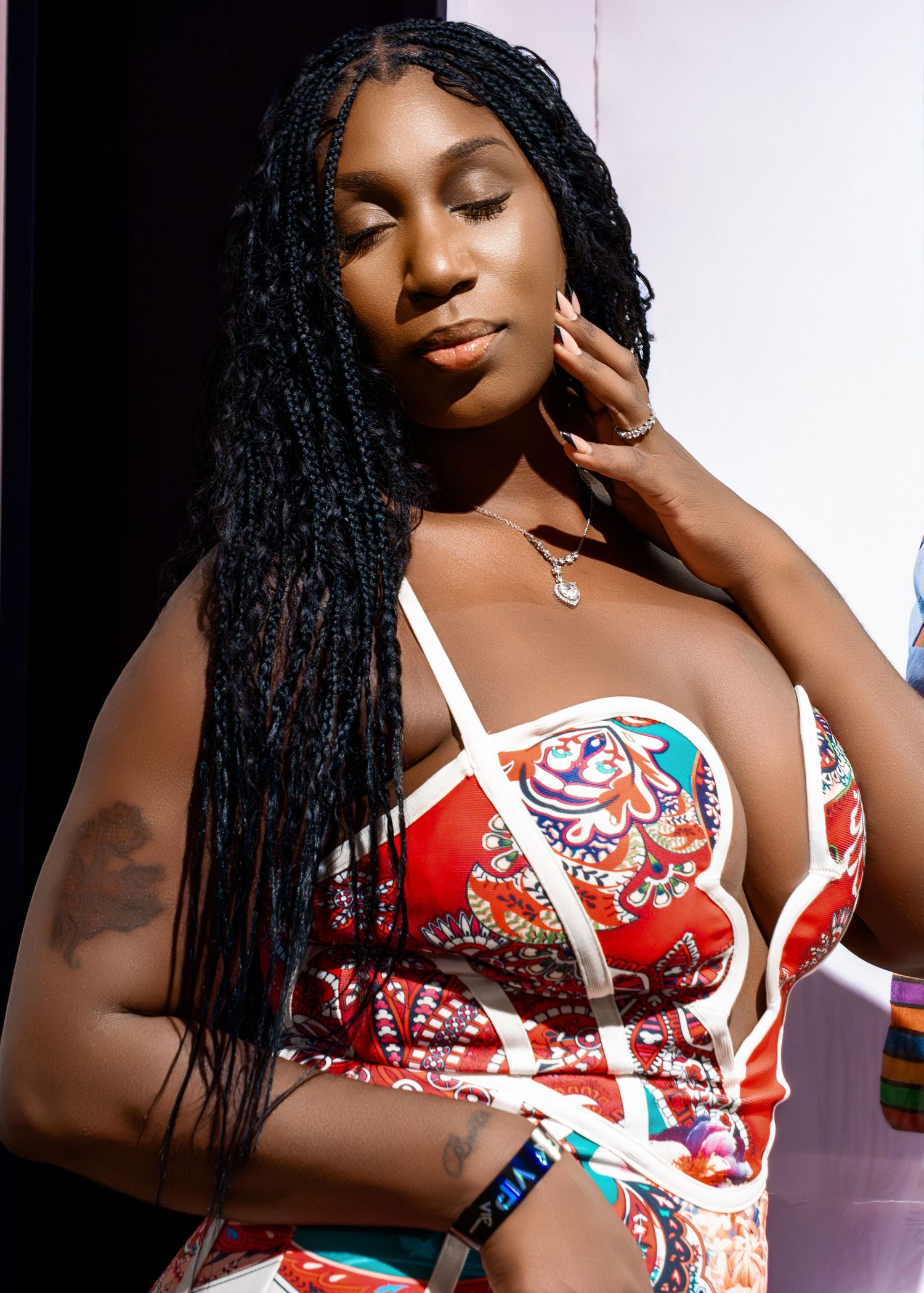 Fashion model poses in vibrant red and white floral print dress against light background.
