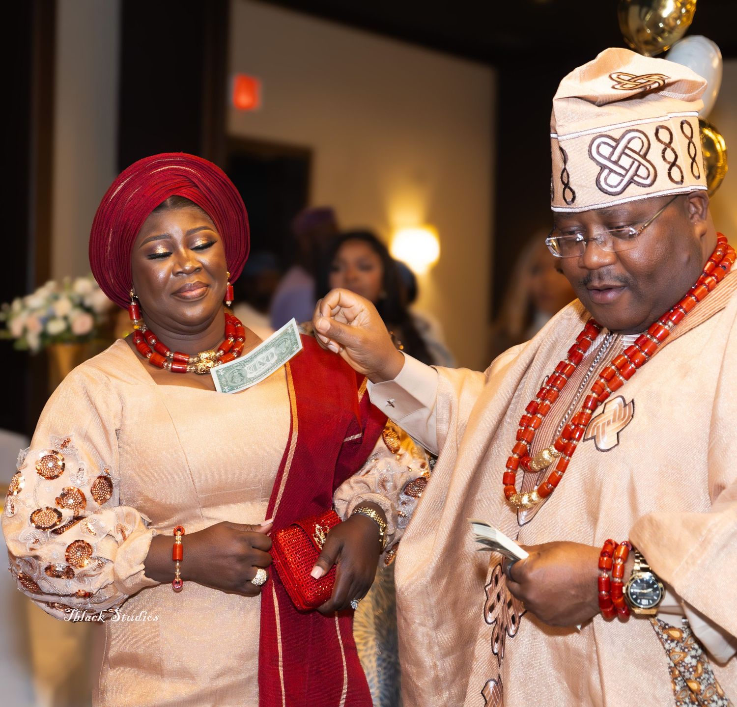 Cultural celebration featuring guests in matching white and cream traditional outfits with red accents.