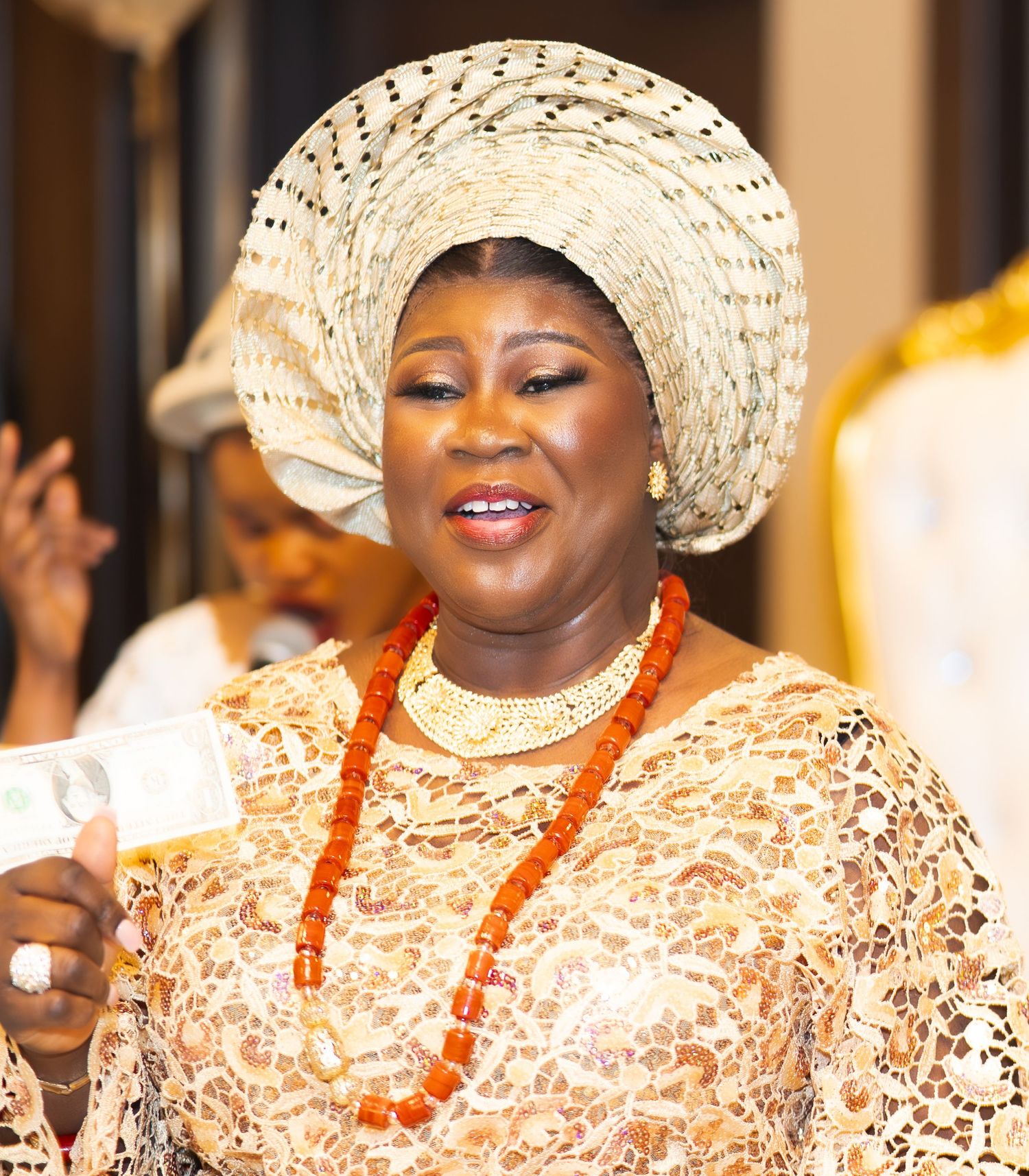 Wedding celebration featuring traditional Nigerian fashion with cream lace and coral bead accessories.