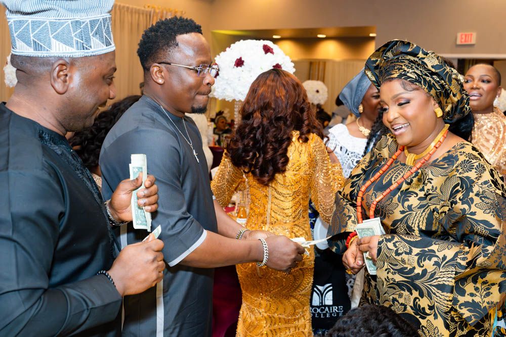 Reception venue filled with guests in traditional African formal wear celebrating together.