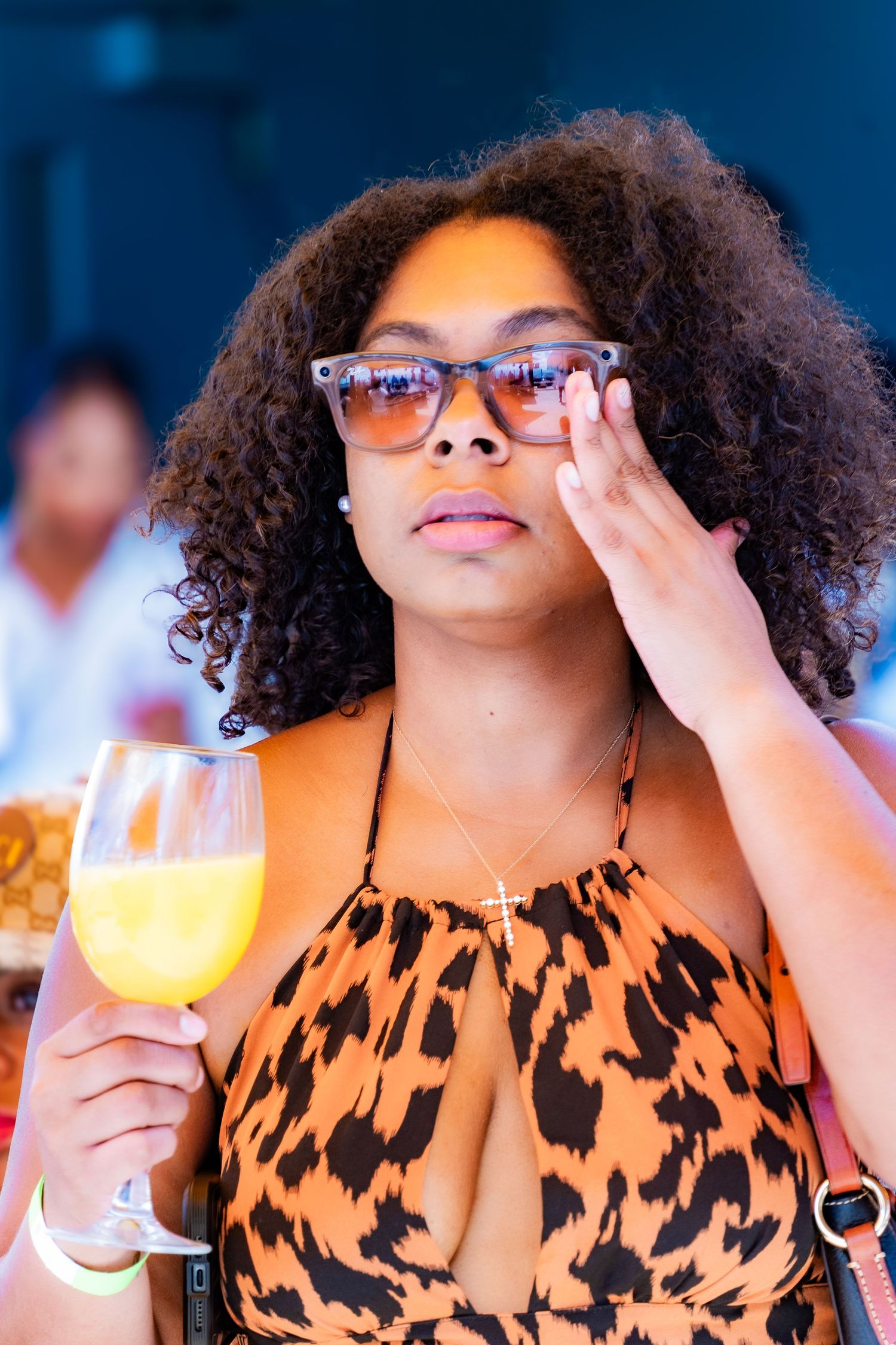 Woman in animal print dress holding mimosa at outdoor brunch event.