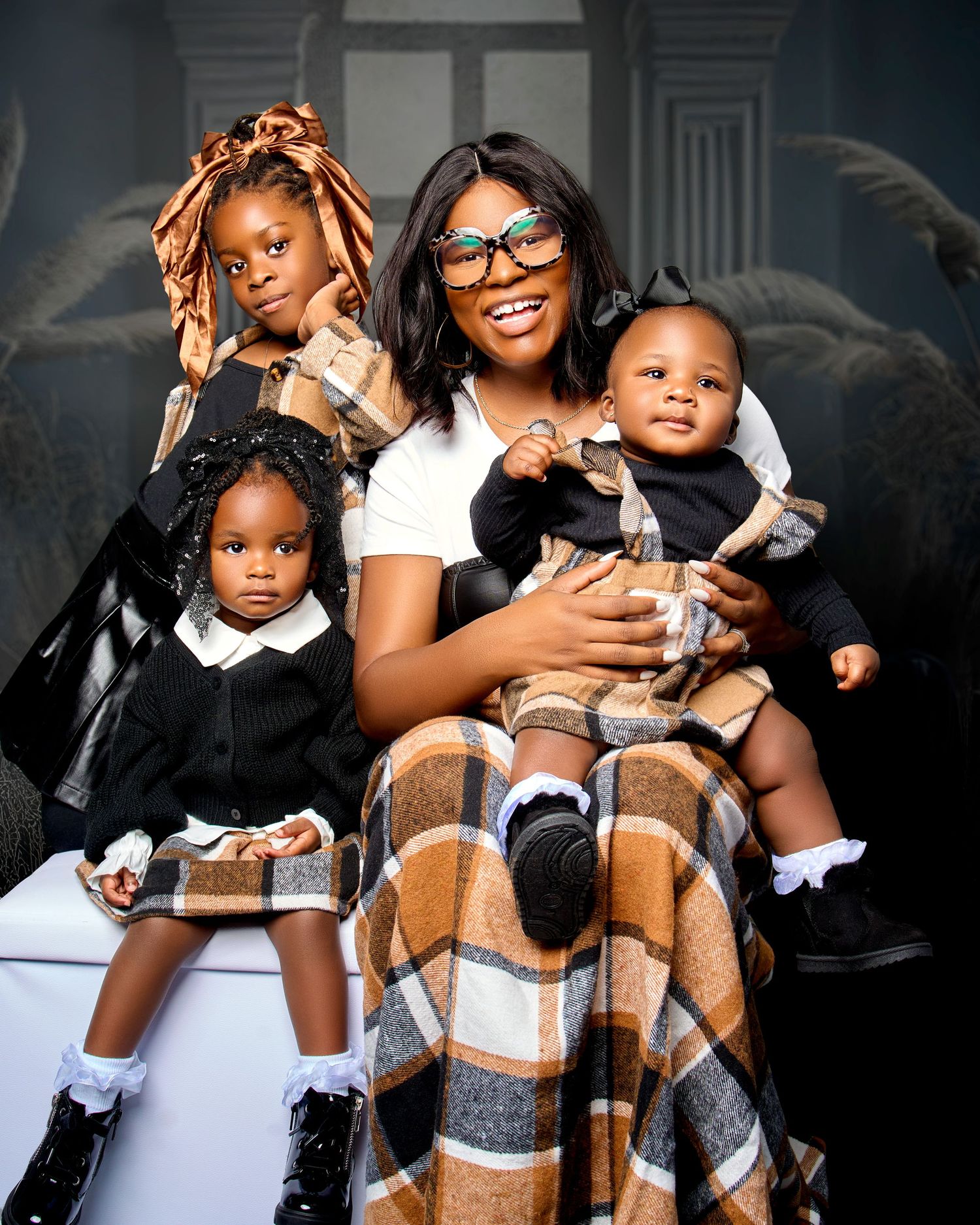 Family portrait showing mother and children sitting together with a cozy plaid blanket.