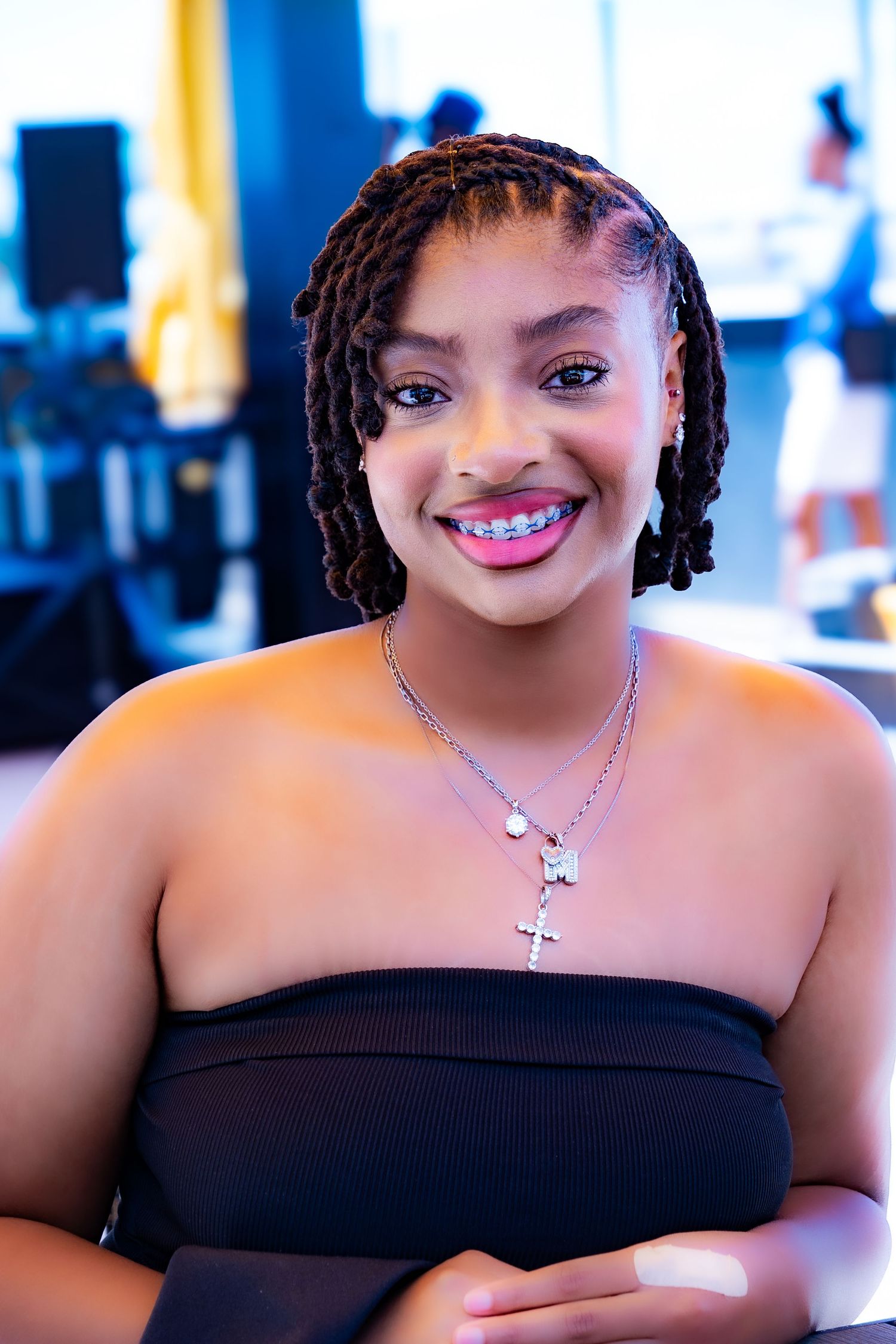 Portrait of woman with braided hair wearing black top and necklace.