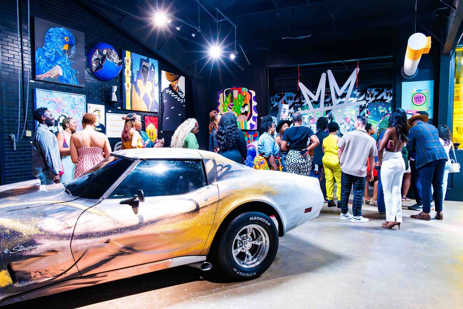 Vintage cars on display in a dark indoor space with spotlights and crowd.