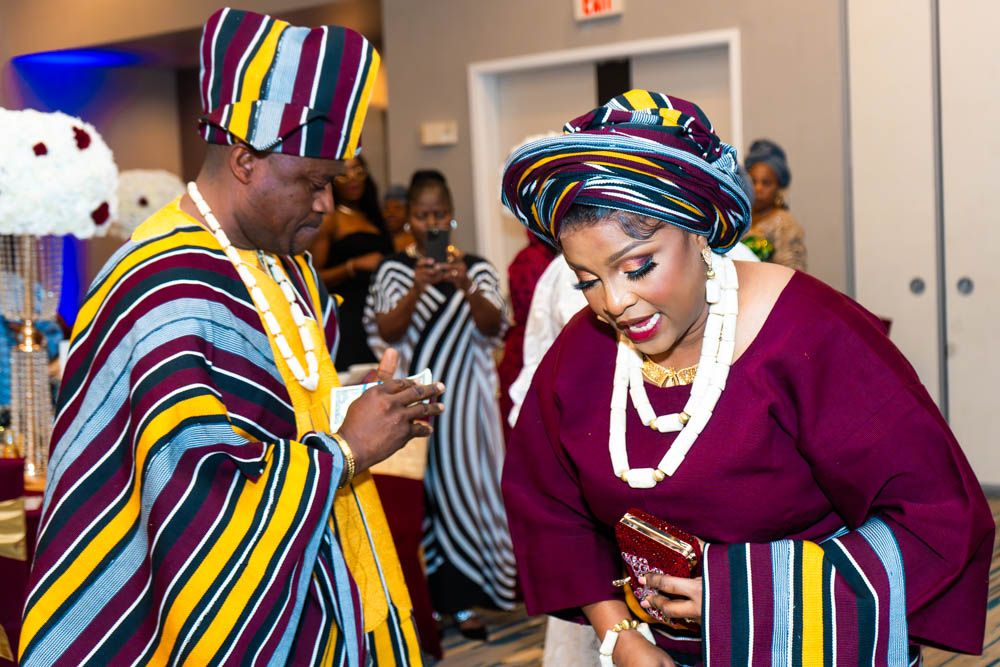 Joyful moment at wedding reception with guests wearing vibrant multicolored traditional African clothing.