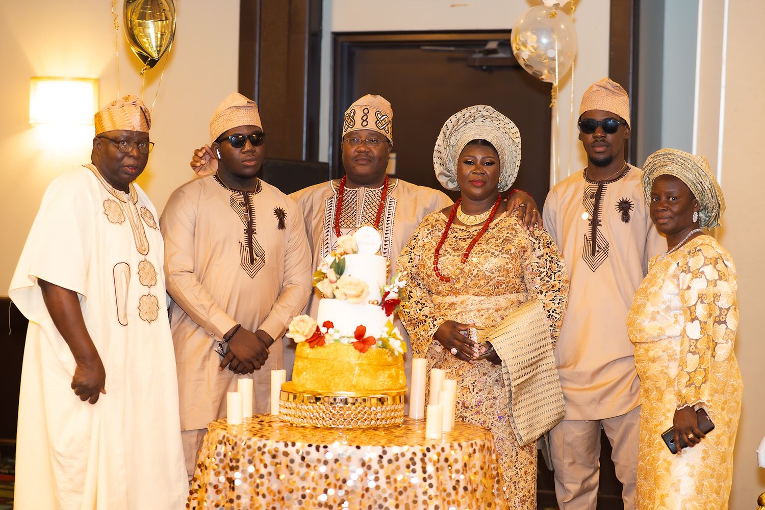 Elegant African celebration showing guests in traditional formal wear gathered in a warmly lit venue.