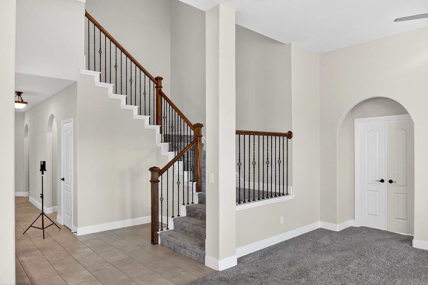 Open living space with carpeted stairs, wrought iron balusters, and wooden handrails.
