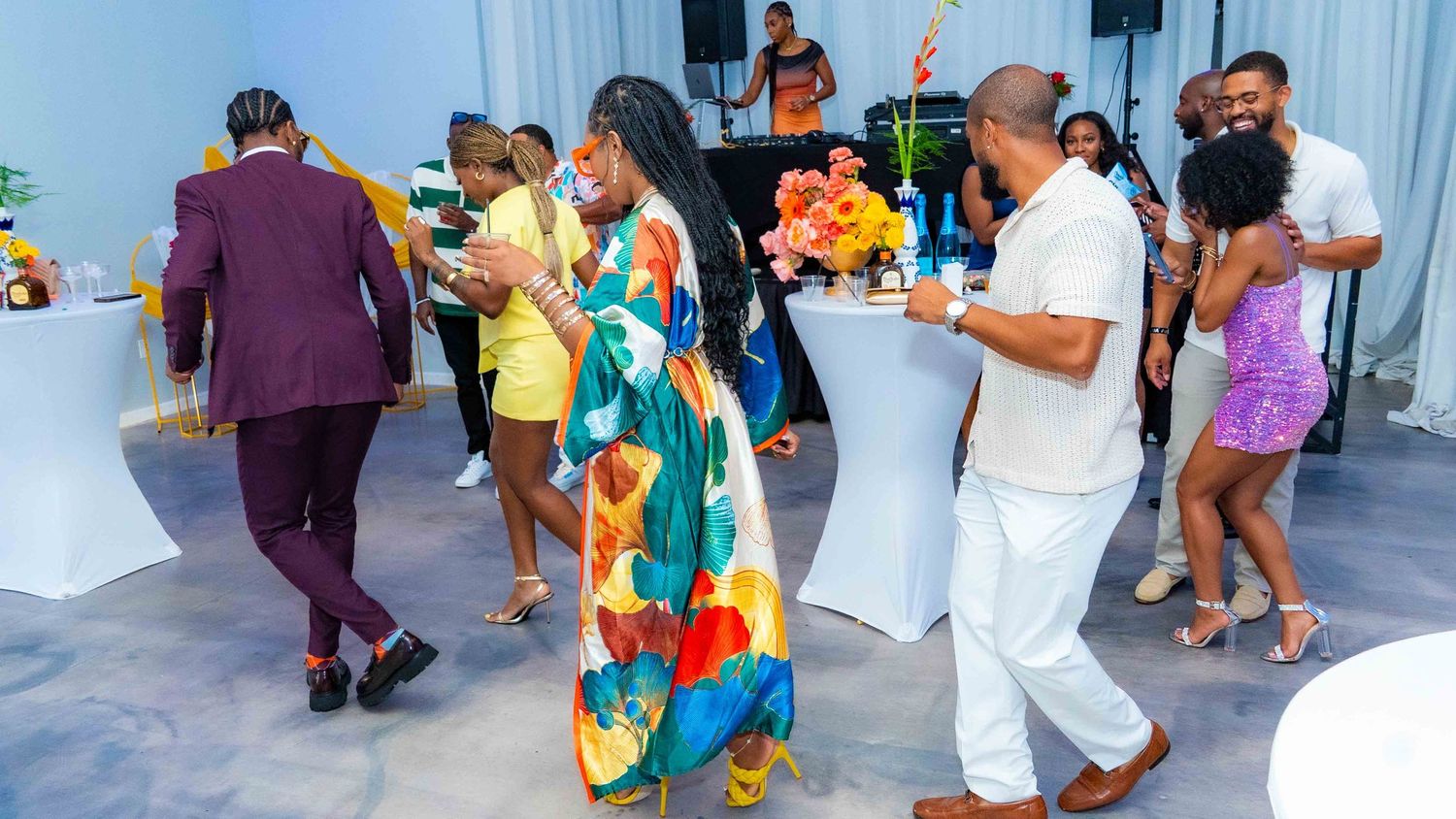 People dancing and enjoying themselves at a party with speakers and decorations in the background.