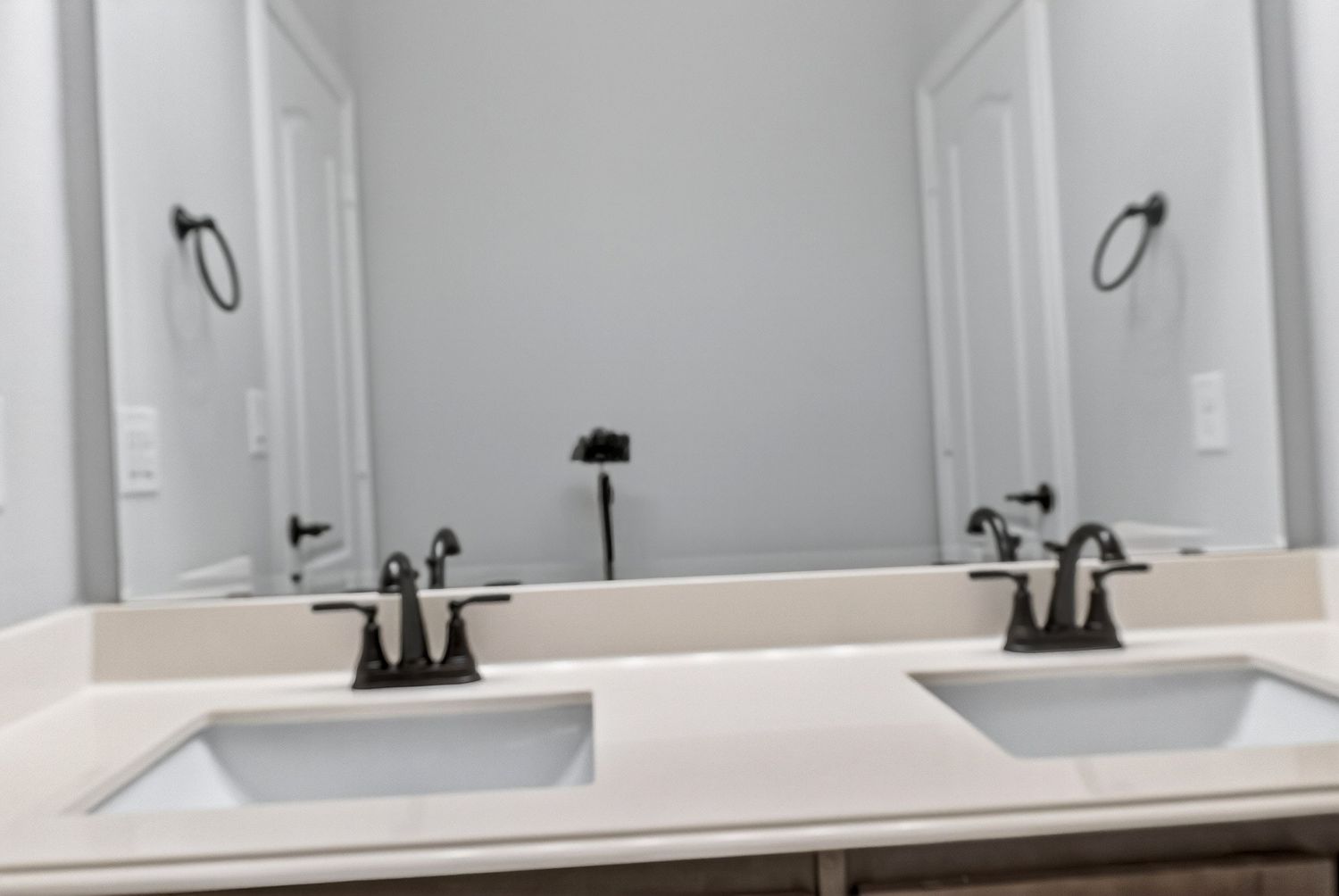 White bathroom countertop with double sinks and matte black fixtures.