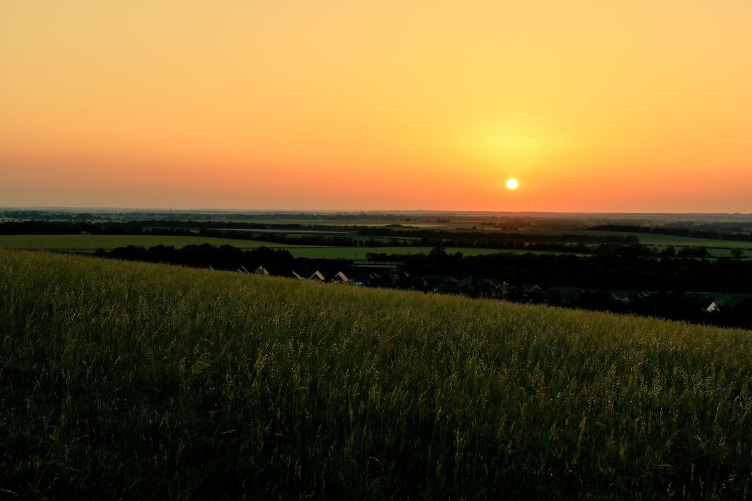 The sun prepares to set over the horizon at Therfield Heath, Royston as scenic golden hour photography are available as wall art prints.