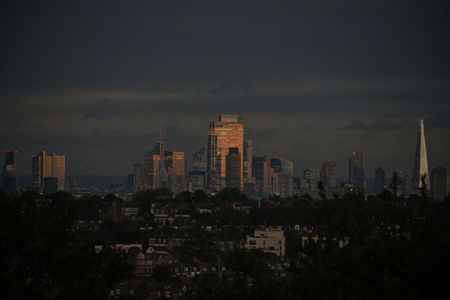 Cloudy city buildings from a far distance as night falls as urban photography available as fine art prints