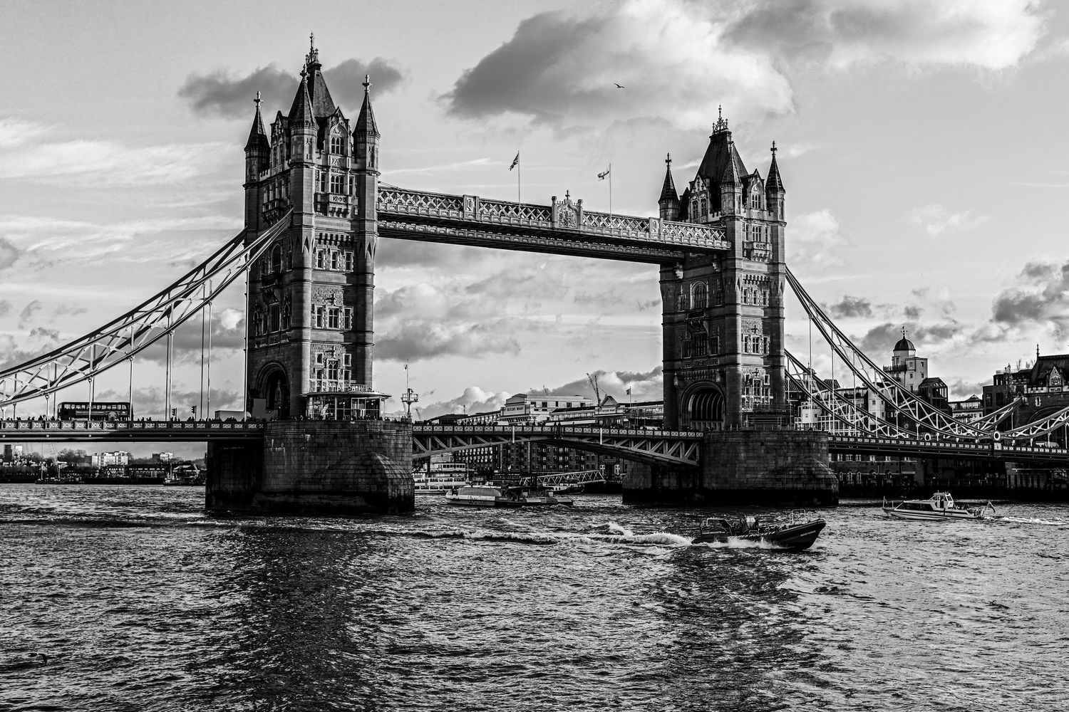 Mini boat passes under Tower Bridge as black & white city photography available as fine art prints and gallery frame.
