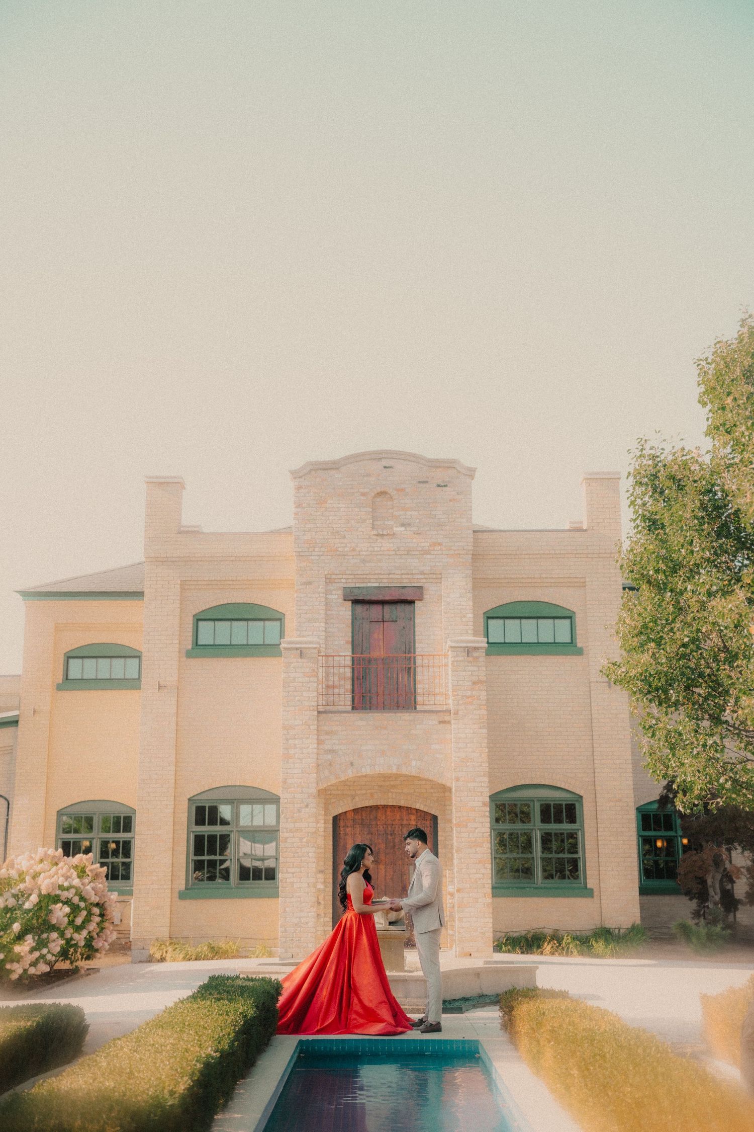 A series of outdoor wedding photos featuring a bride in a red gown posing in front of a beige stone building.