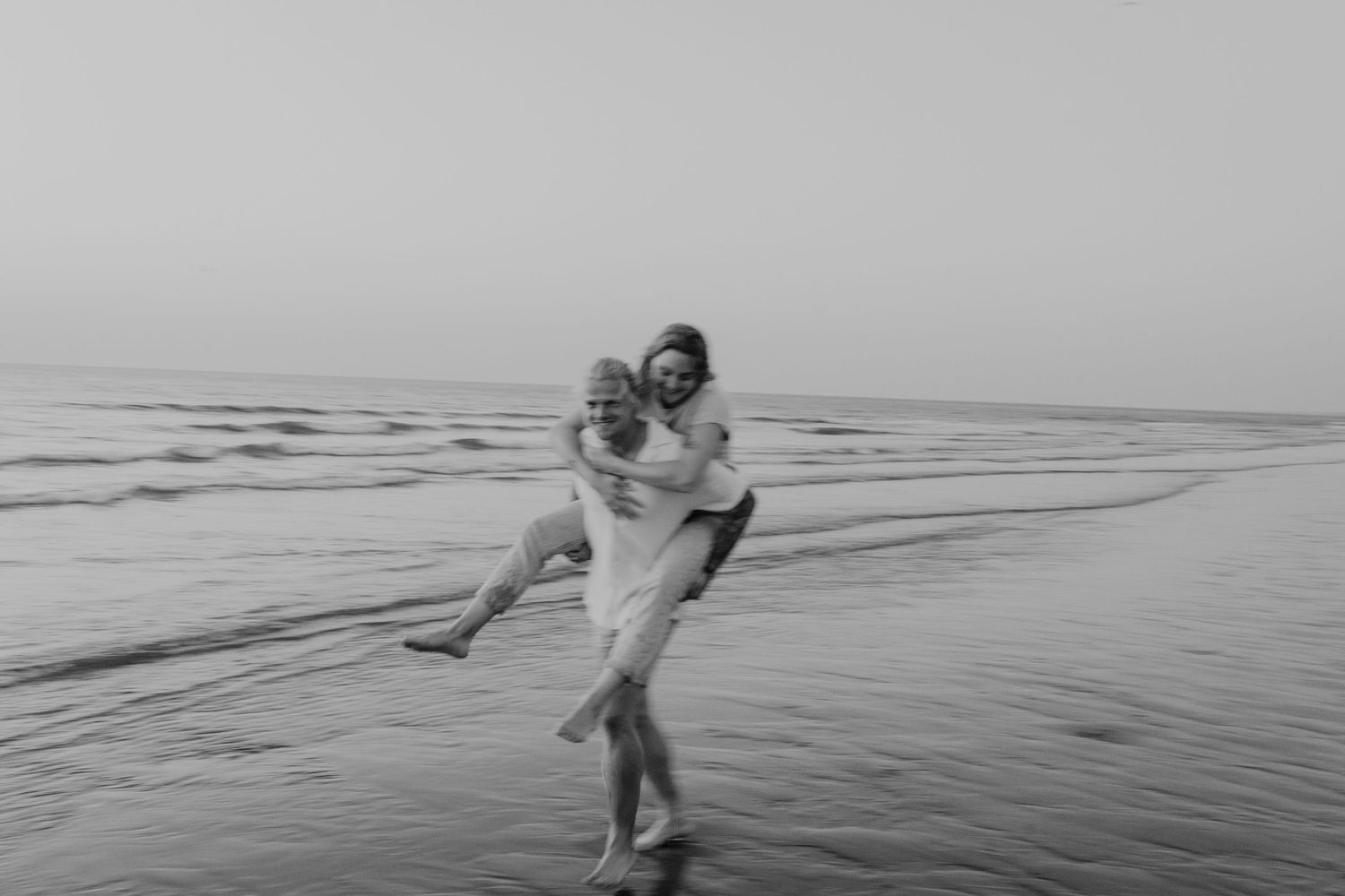Avontuurlijk koppel dat door de branding van de zee rent tijdens een coupleshoot