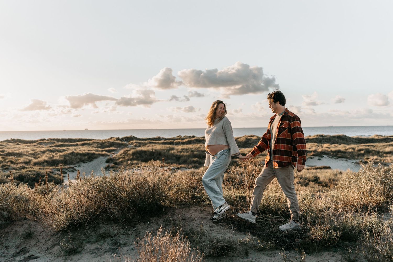 Adventurous pregnant couple at the beach during golden hour