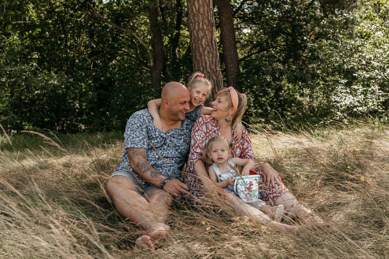 Gezin tijdens een familieshoot spelend in het gras met zacht natuurlijk licht