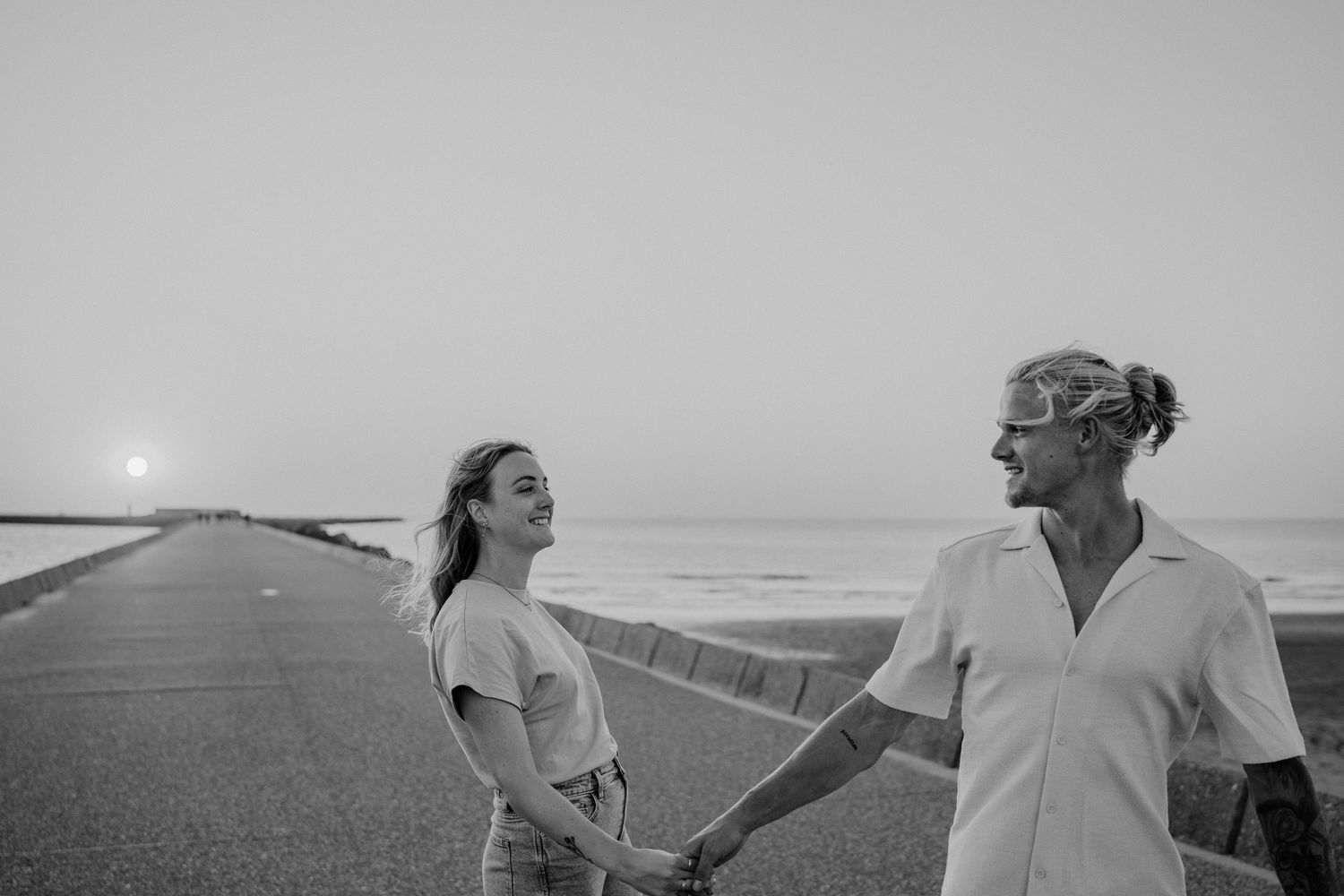 Zwart-wit foto van verliefd koppel tijdens een fotoshoot aan het strand met ondergaande zon