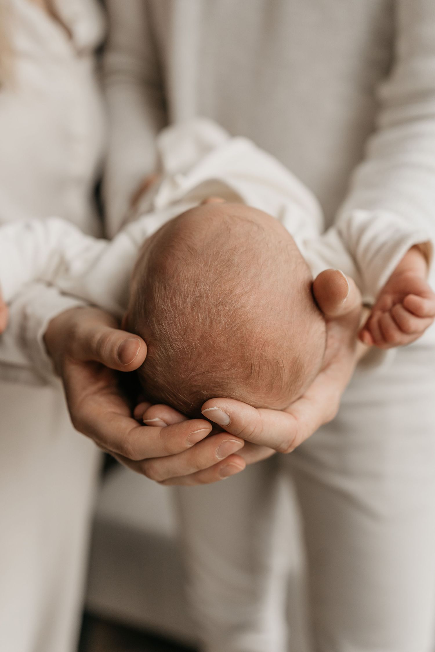 Detailfoto van newborn die wordt vastgehouden voor handen van vader en moeder