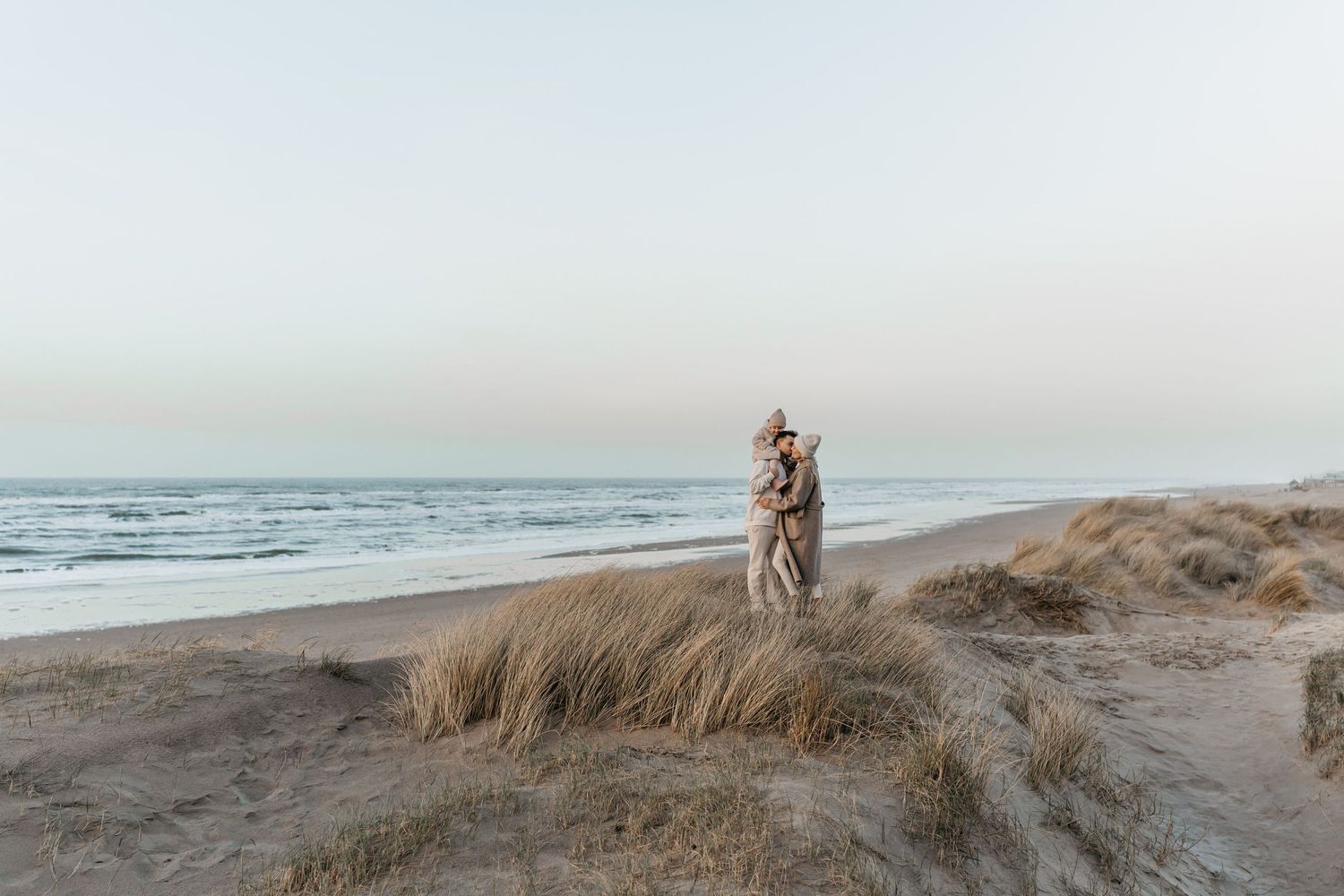 Zwangerschapsshoot in de winter aan het strand tijdens golden hour