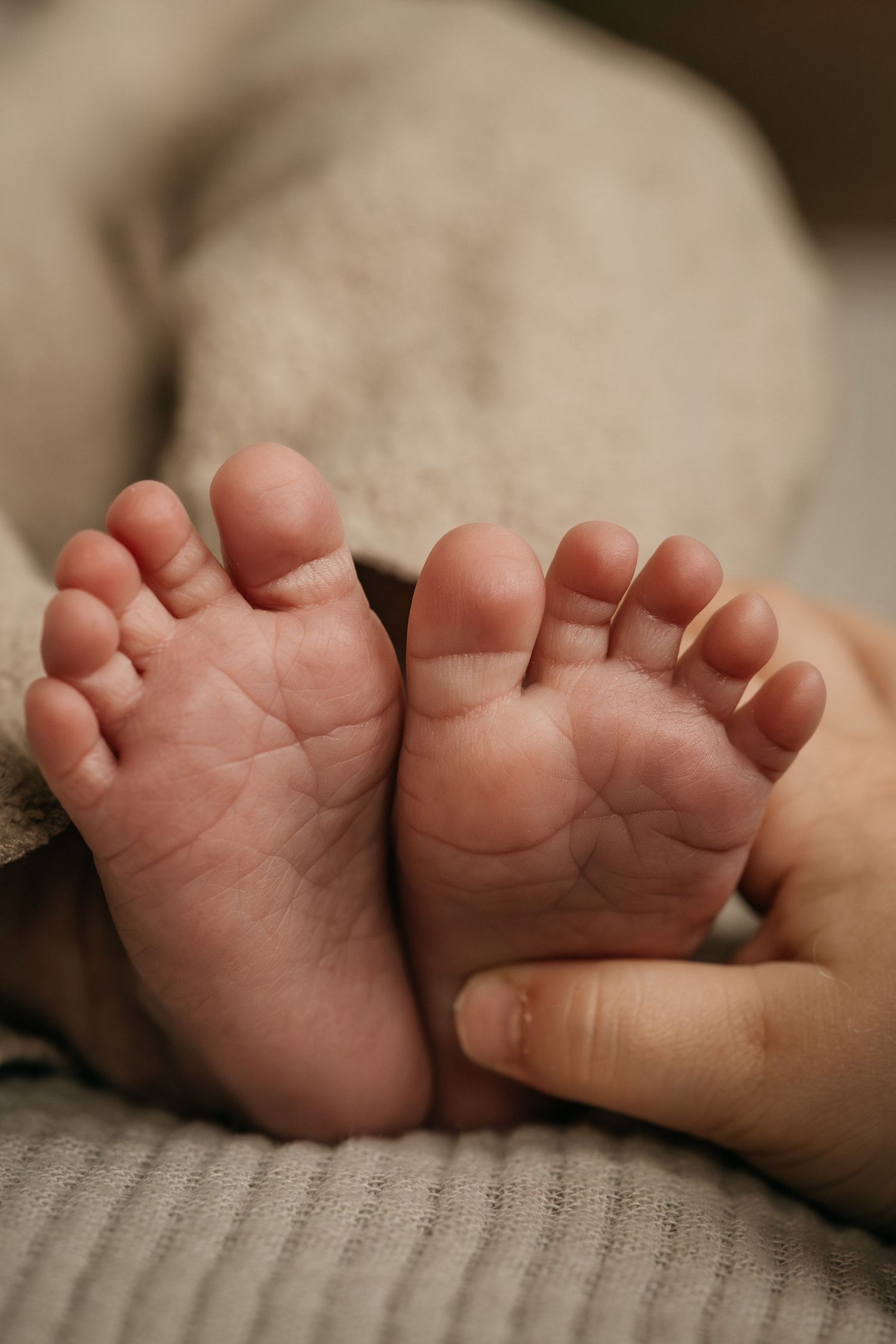 Grote zus houdt voetje vast van pasgeboren broertje tijdens een newbornshoot thuis in Noord-Brabant