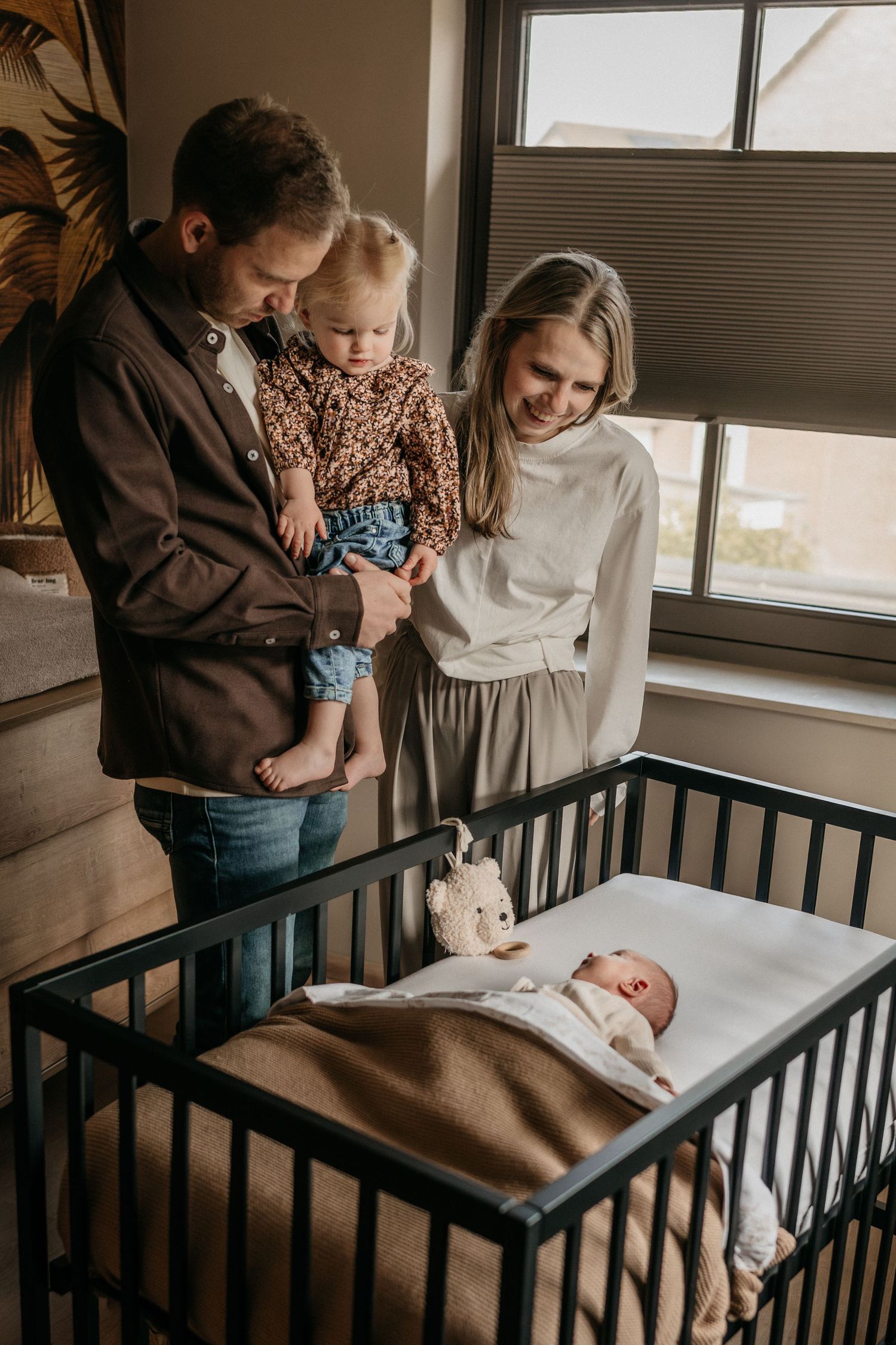 Newbornshoot waarbij zus bij kleine zusje gaat kijken met ouders