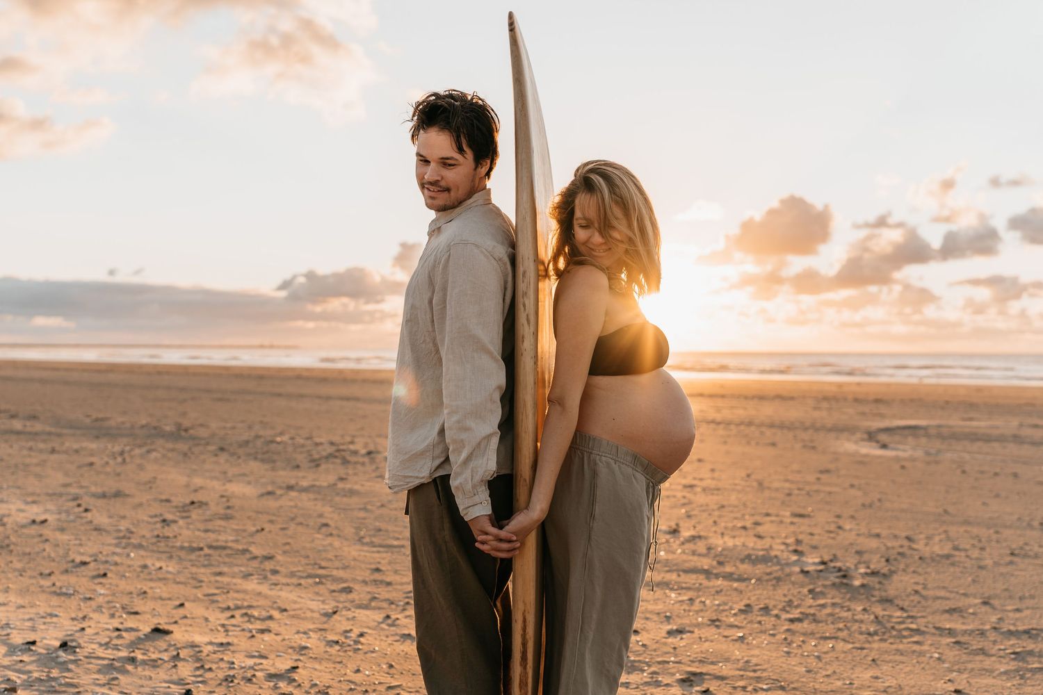 Pregnant surfers couple during beach shoot