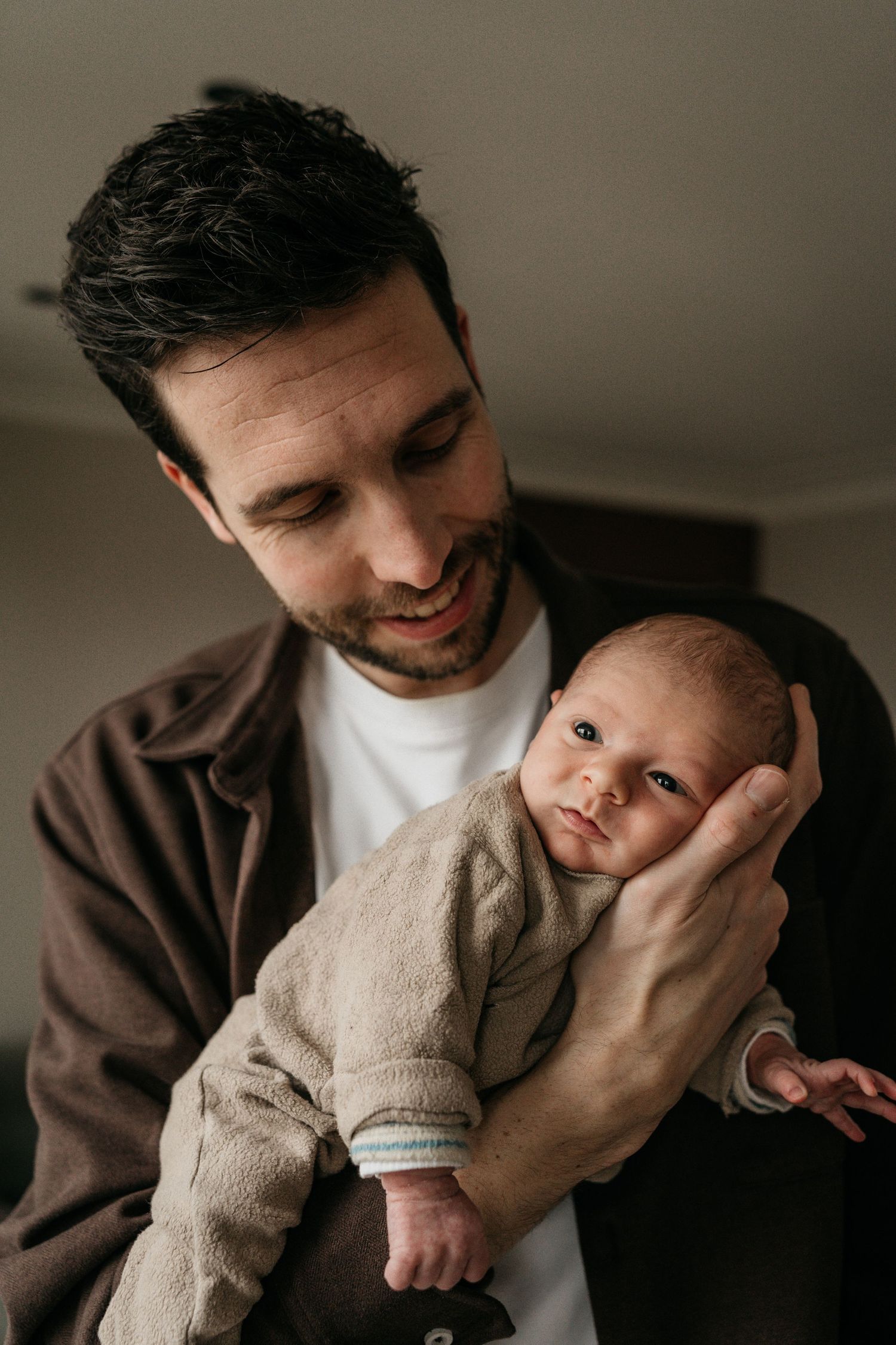 Newbornshoot waarbij vader pasgeboren zoon vasthoudt in natuurlijk licht