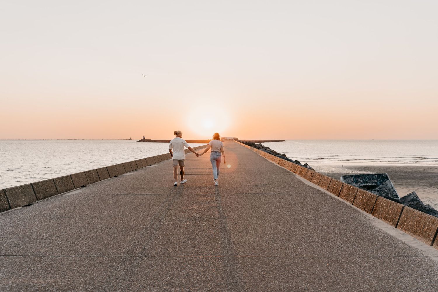 Koppel op een ruige pier aan zee tijdens een coupleshoot met zonsondergang