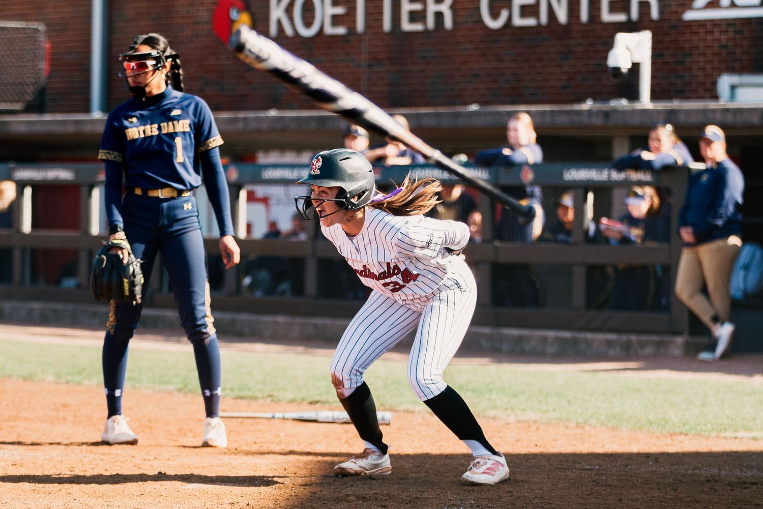 Baseball player swings bat at home plate during collegiate game against University of San Diego.