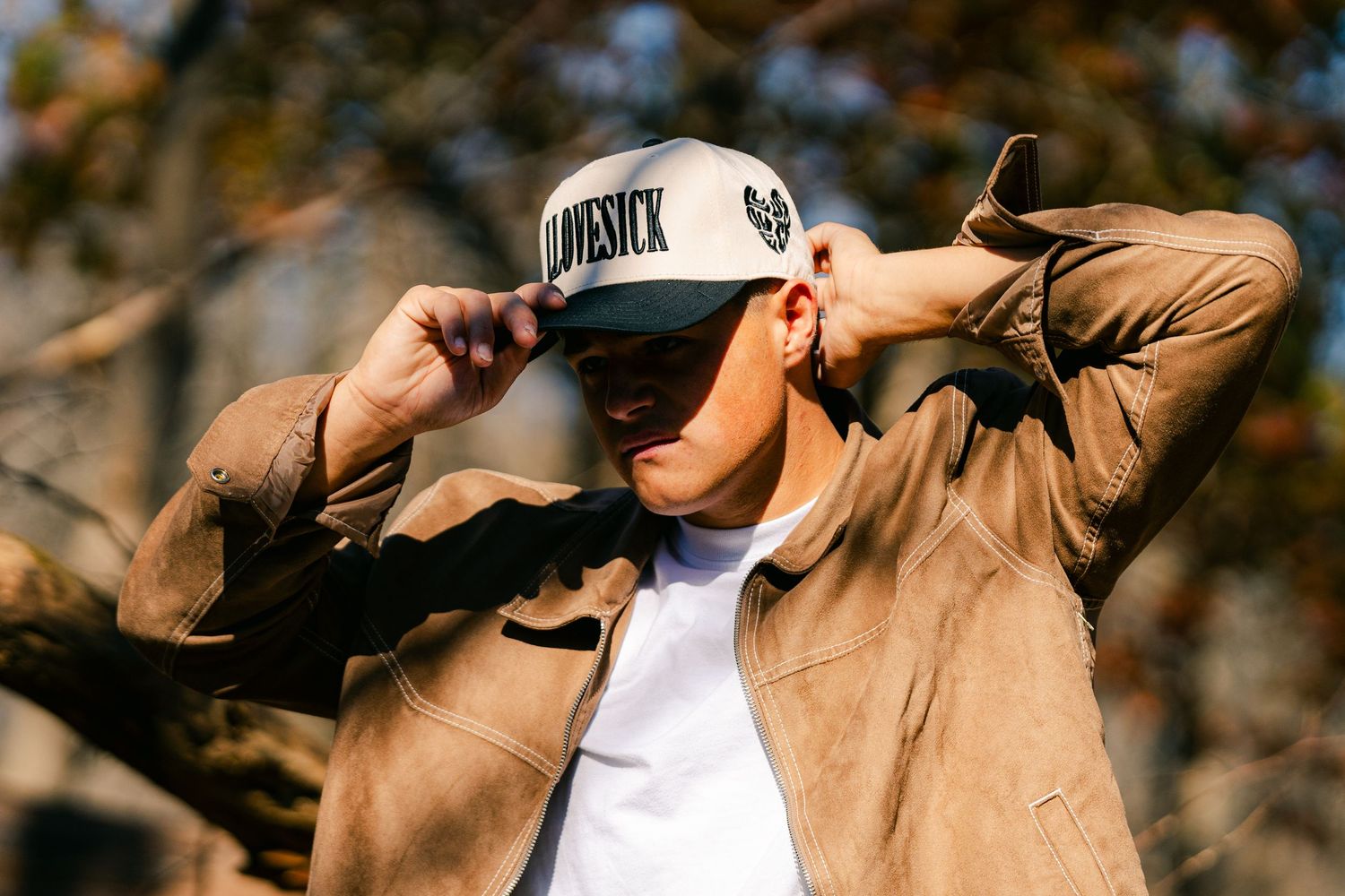 Figure in tan jacket and white cap photographed in silhouette against bright background.