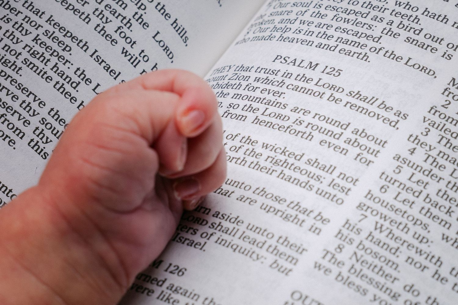 Close up of hands of baby on a page in the Bible.