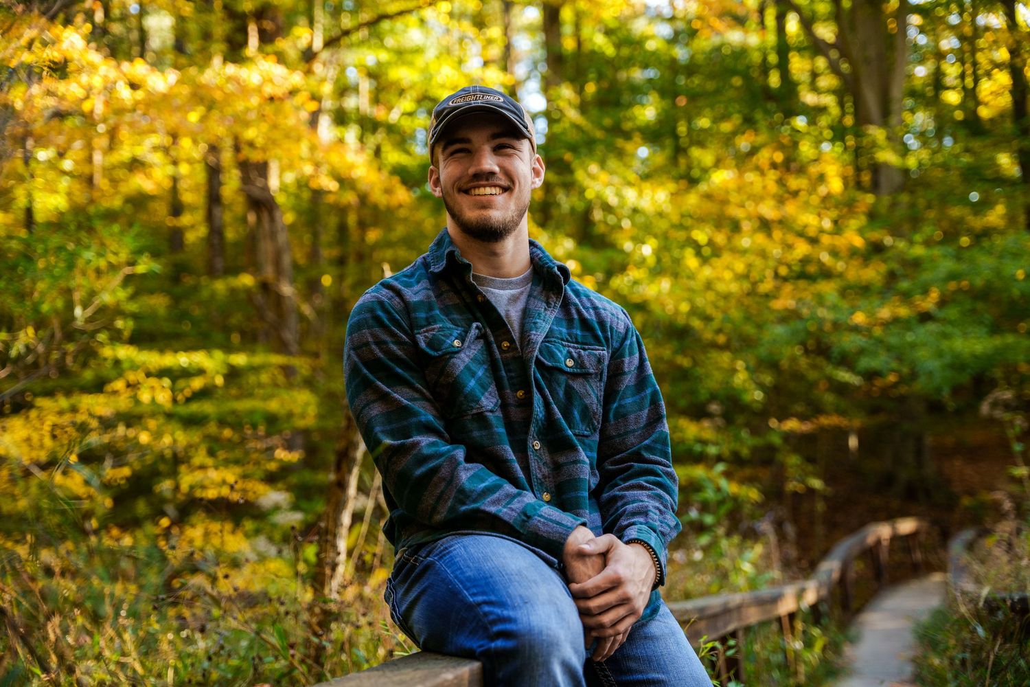 Candid outdoor portrait session in wooded area with golden autumn lighting.